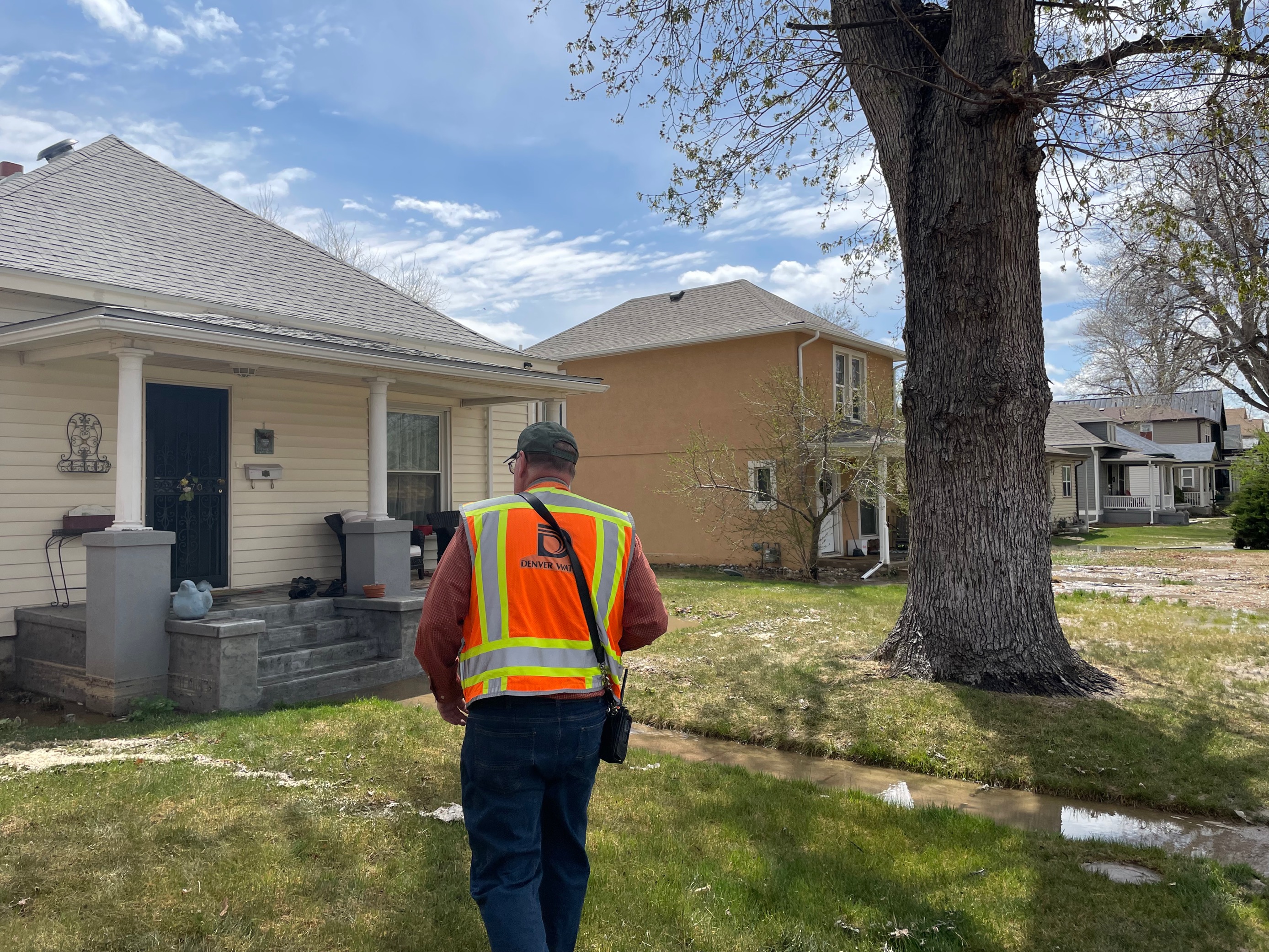 A Denver Water technician approaches a resident's home after a water main break flooded streets and lawns in the Berkeley neighborhood Sunday, April 24, 2022. (Lindsey Toomer, Denver Gazette) (Lindsey Toomer, Denver Gazette)