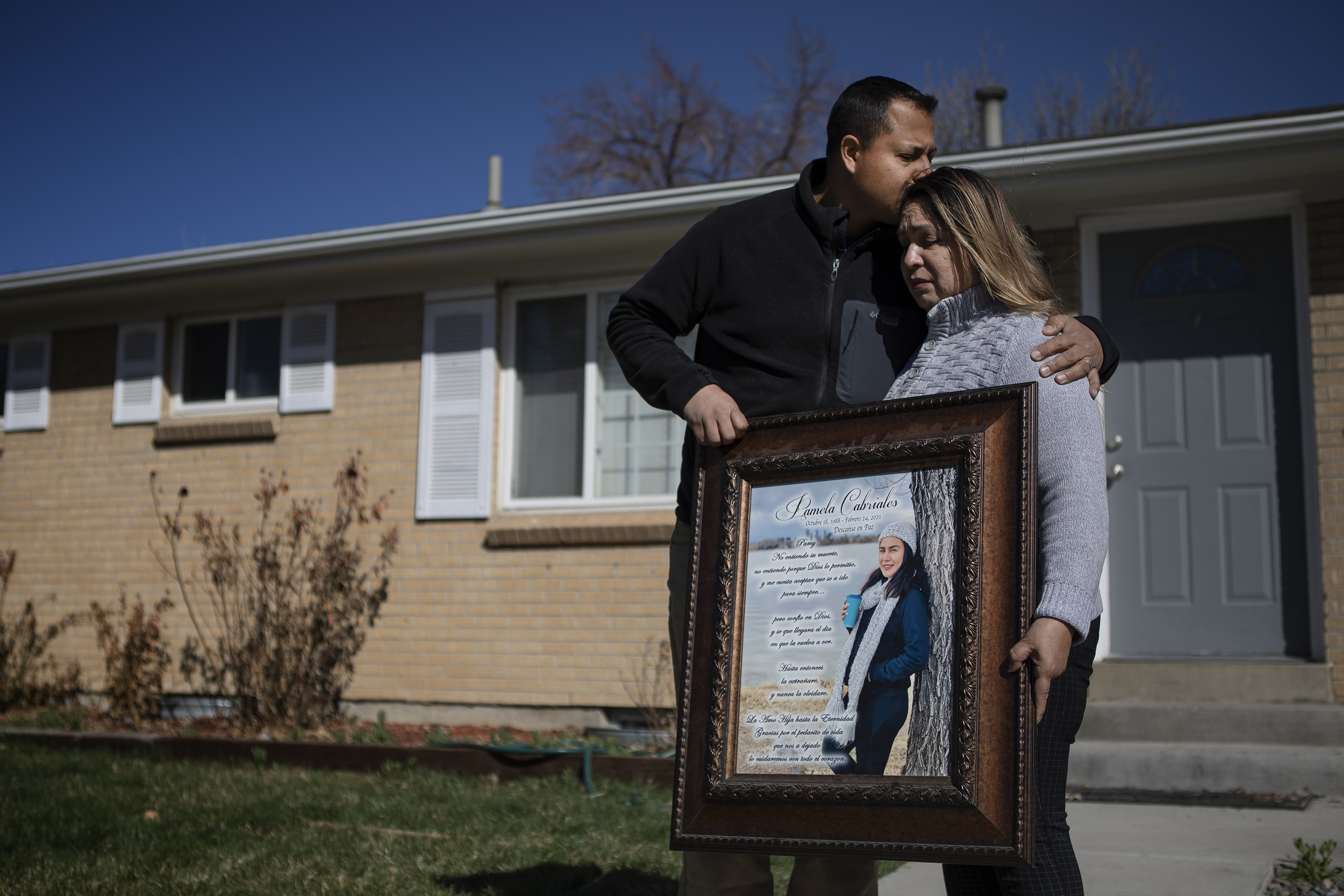 Alex Cabriales leans in to comfort his mother Irma Cabriales while the two hold a portrait of their sister and daughter Pamela Cabriales.  She was shot to death Feb. 24, 2021. (Timothy Hurst/The Denver Gazette) (Timothy Hurst/Denver Gazette)