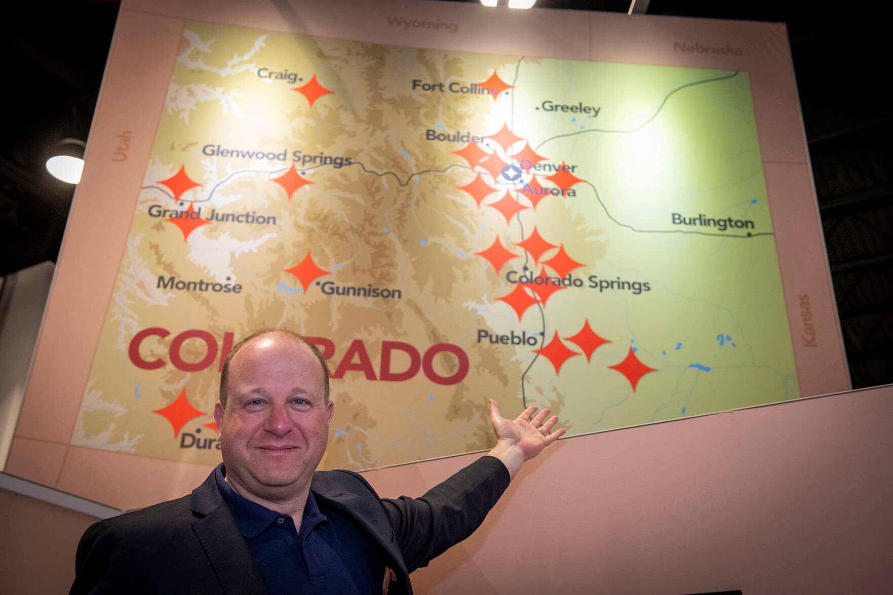 Colorado Gov. Jared Polis shows off the new state map with the AerospaceCO branding. The red stars indicate where aerospace companies are located. (Courtesy of the Space Foundation/CHUCK BIGGER)