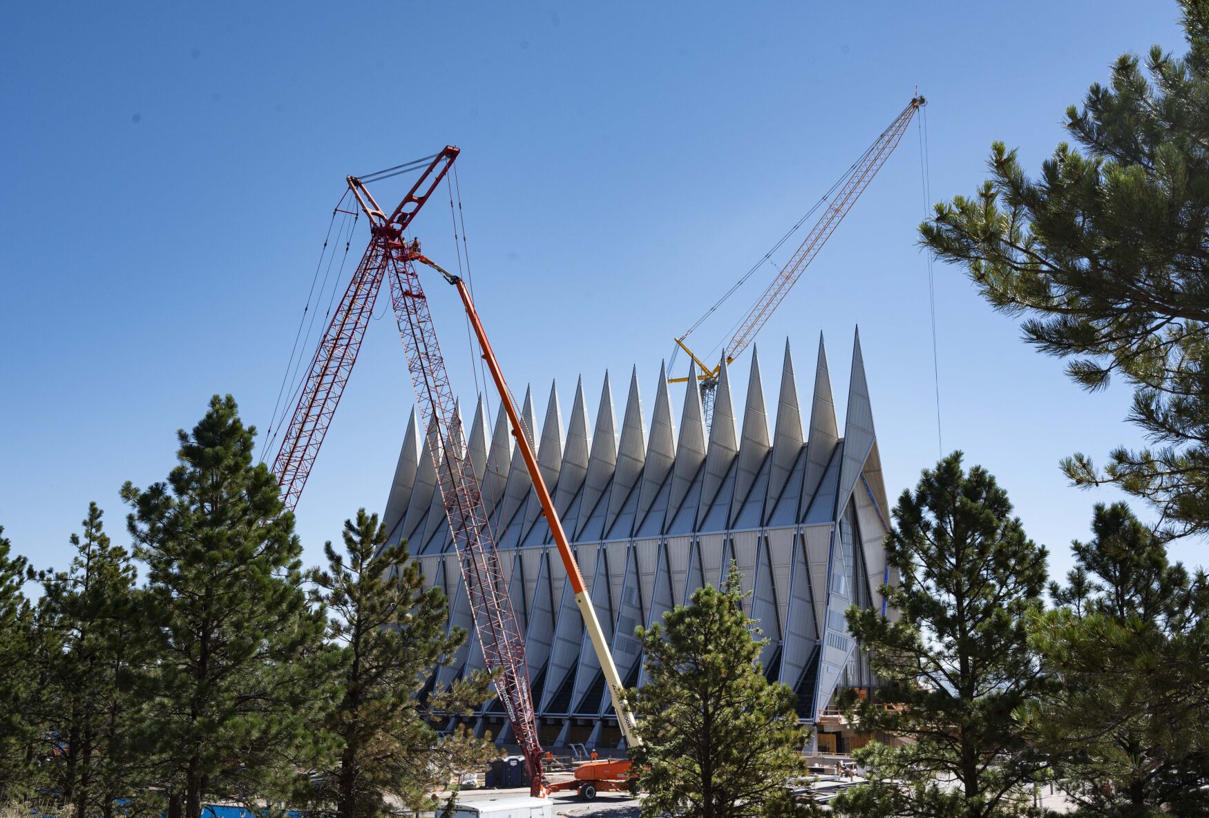 Crews work on the cranes Friday, Aug. 7, 2020, that will be used to construct a large hanger, similar to the structure at Denver International Airport, over the U.S. Air Force Academy Cadet Chapel as part of the complete restoration and renovation of the chapel designed by American Architect Walter Netsch. (Christian Murdock, The Gazette)