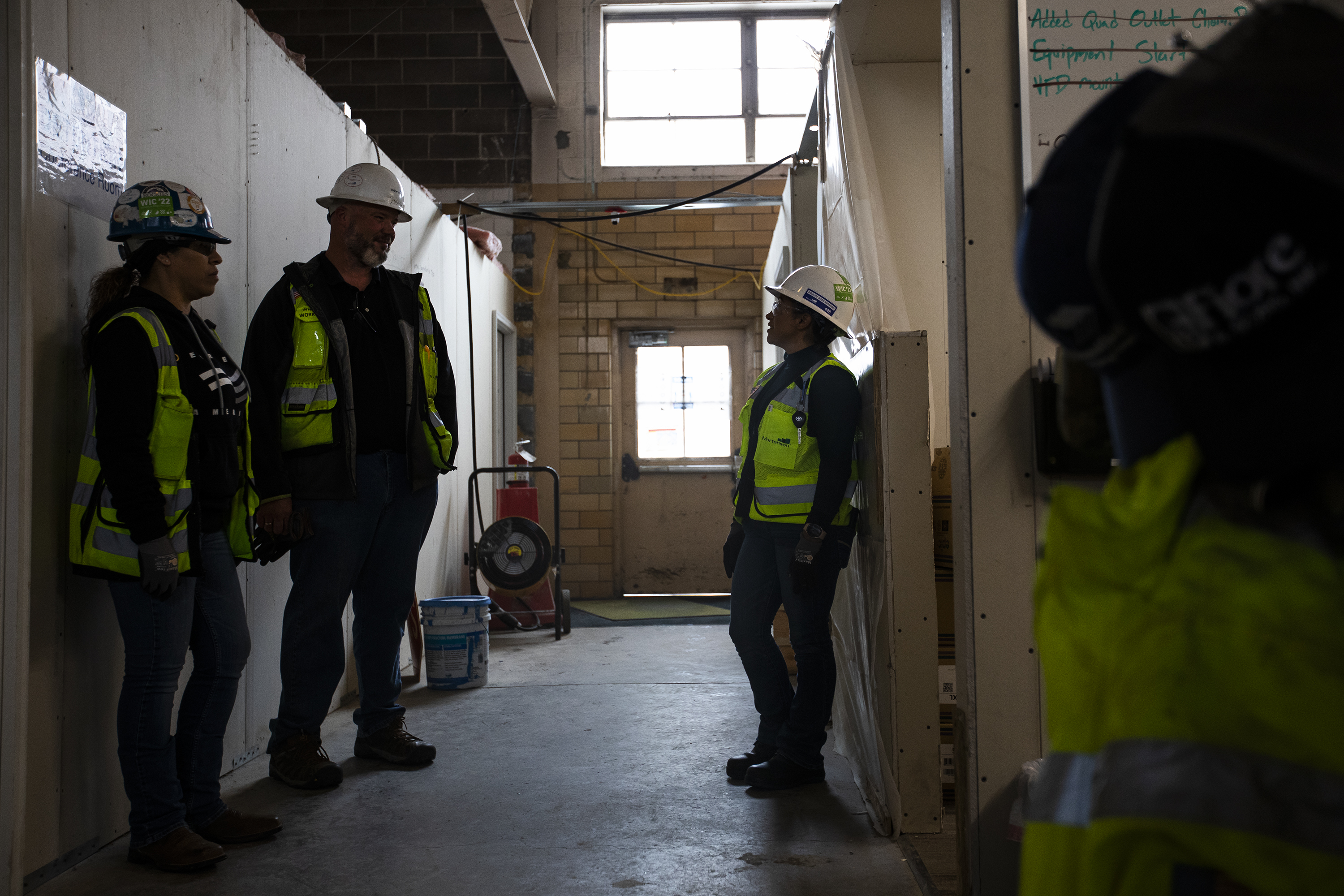 Mortenson Construction employees, from left, general foreman Claudia Saucedo, superintendent Flint Putnam and carpenter Maria Gallegos talk in a hallway between temporary construction offices in a Glenarm building on the Emily Griffith Hotel Redevelopment site on Thursday, March 17, 2022, in Denver. (Timothy Hurst/The Denver Gazette) (Timothy Hurst/The Denver Gazette)