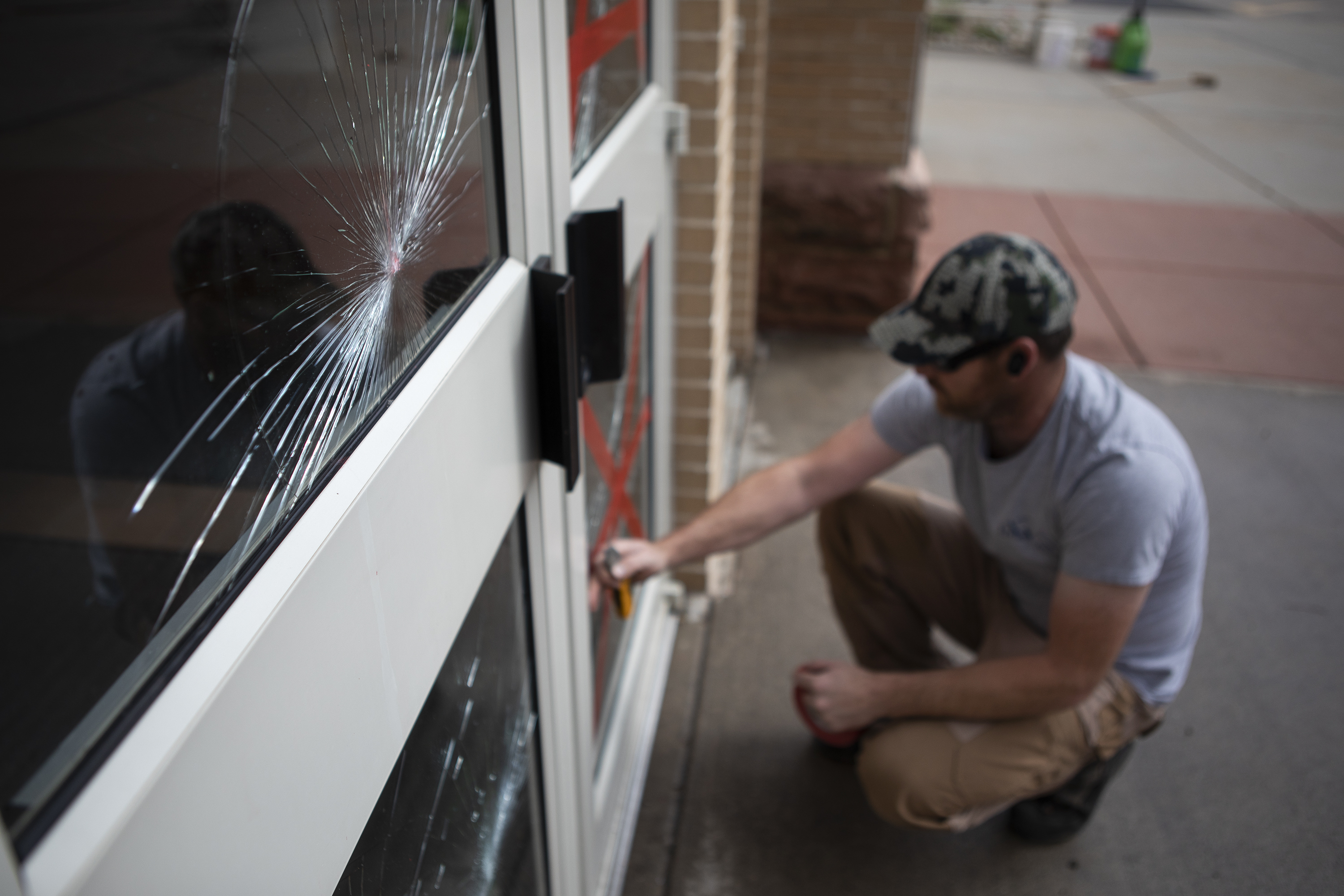 Andrew Neitenbach with Horizon West Builders uses tape to stabilize broken glass doors at Sacred Heart of Mary Catholic Parish on Wednesday, May 4, 2022, in Boulder, Colo. Beyond the broken windows, the church had multiple exterior walls and statues spray painted the night before. (Timothy Hurst/The Denver Gazette) (Timothy Hurst)