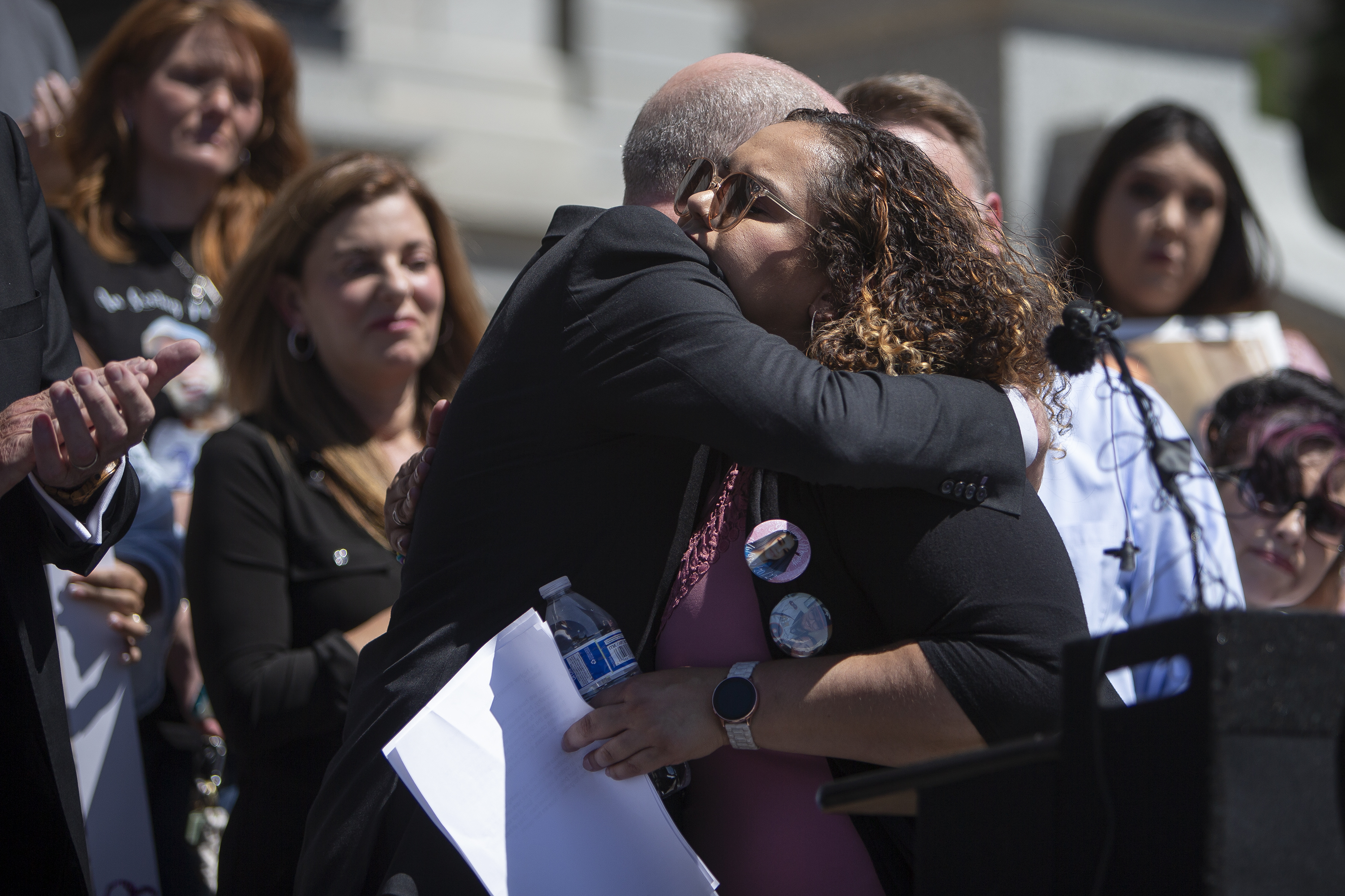 Feliz Sanchez Garcia hugs Brian Mason, district attorney for Colorado's 17th Judicial District, after reading aloud the names of victims of fentanyl poisoning before Gov. Jared Polis, not pictured, signed the HB22-1326 Fentanyl Accountability And Prevention bill on Wednesday, May 25, 2022, on the west steps of the Colorado State Capitol Building in Denver, Colo. (Timothy Hurst/The Denver Gazette) (Timothy Hurst)