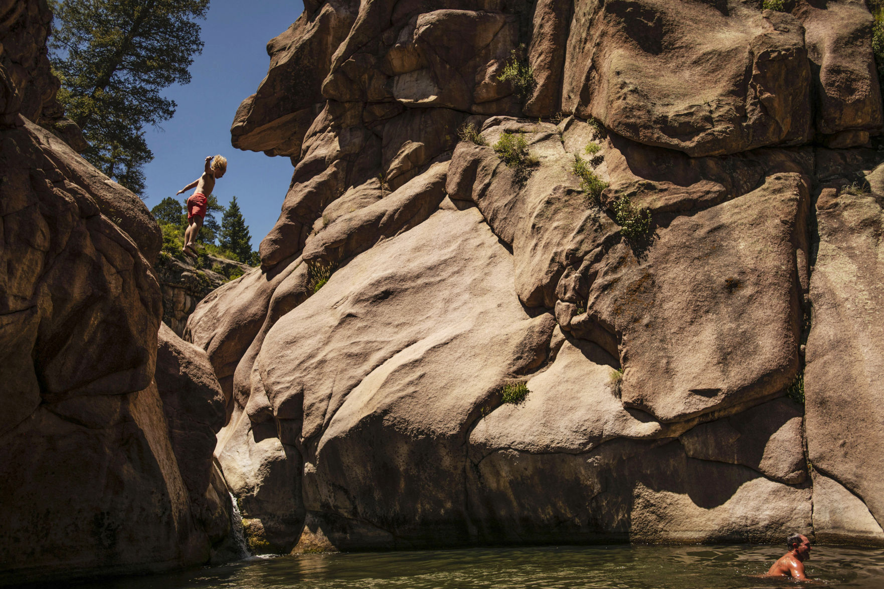 Connor Eise, 17, leaps off the edge of rocks into the water below at Guffey Gorge, also known as Paradise Cove, near the town of Guffey in Park County on Friday, July 5, 2019. Paradise Cove is a popular day-use swimming and cliff jumping spot during the summer months. (Chancey Bush, The Gazette)