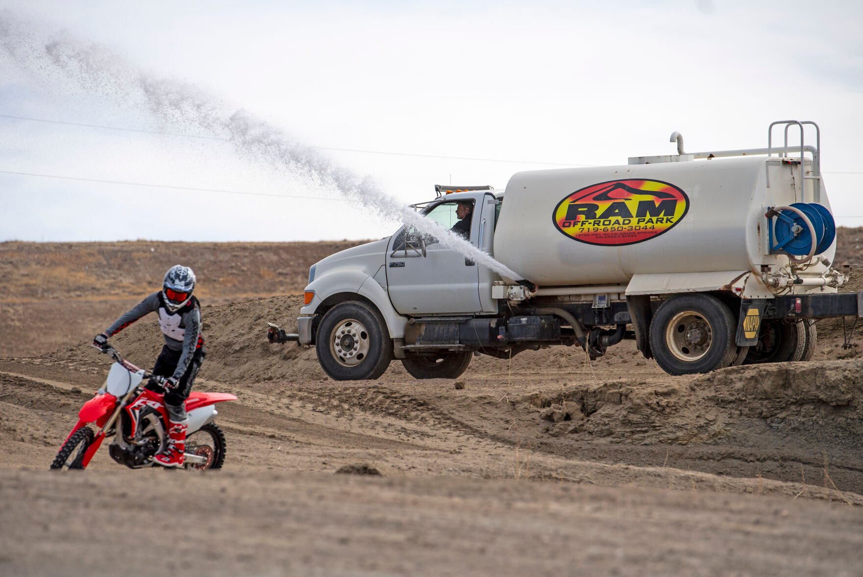 Ray Mandel, owner of RAM Off-Road Park, sprays the kids track with water. Watering the track is a regular part of the maintenance Mandel has to do. (Parker Seibold, The Gazette)