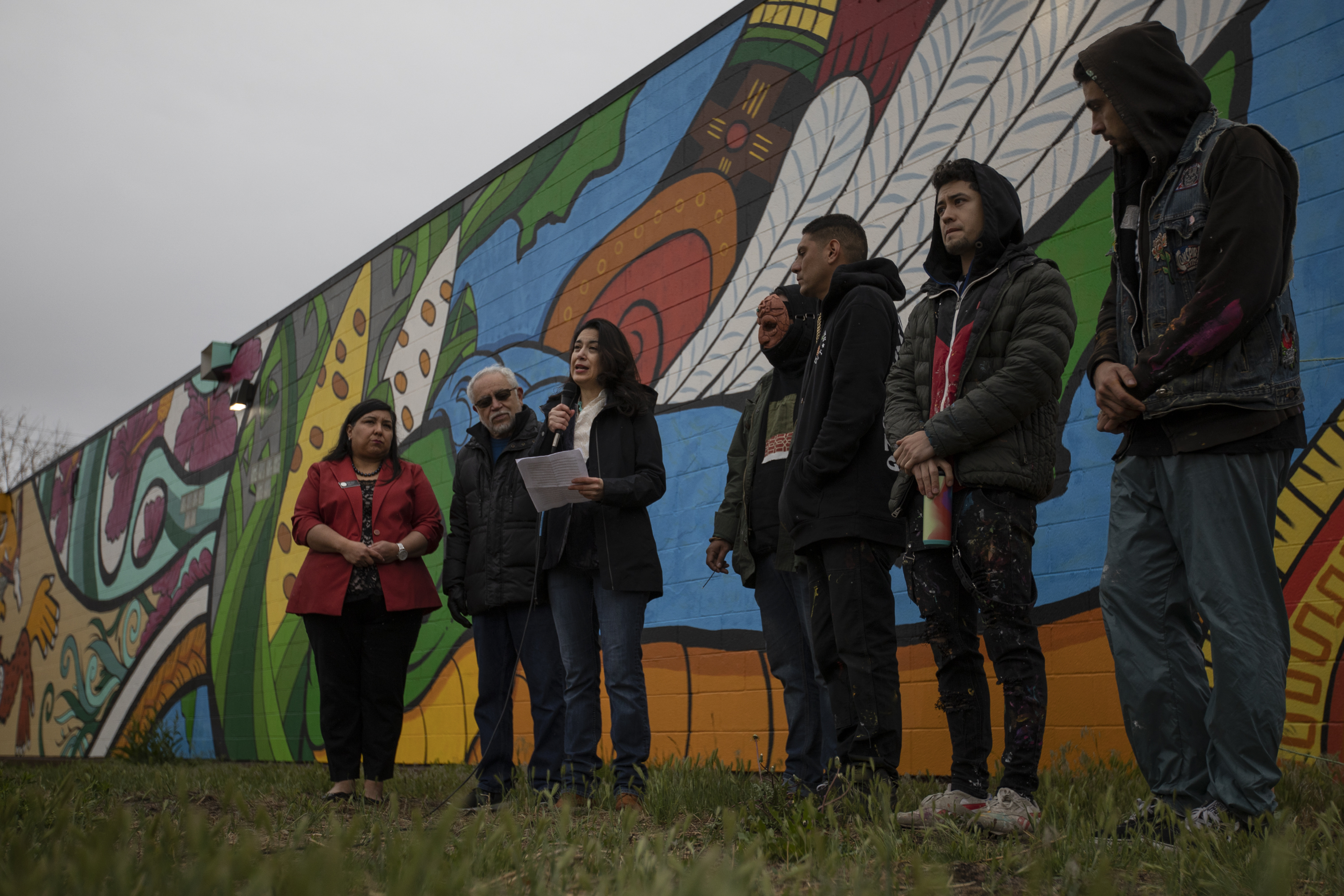 Chicano/a Murals of Colorado Project director Lucha Martínez de Luna, center, speaks in front of the mural 