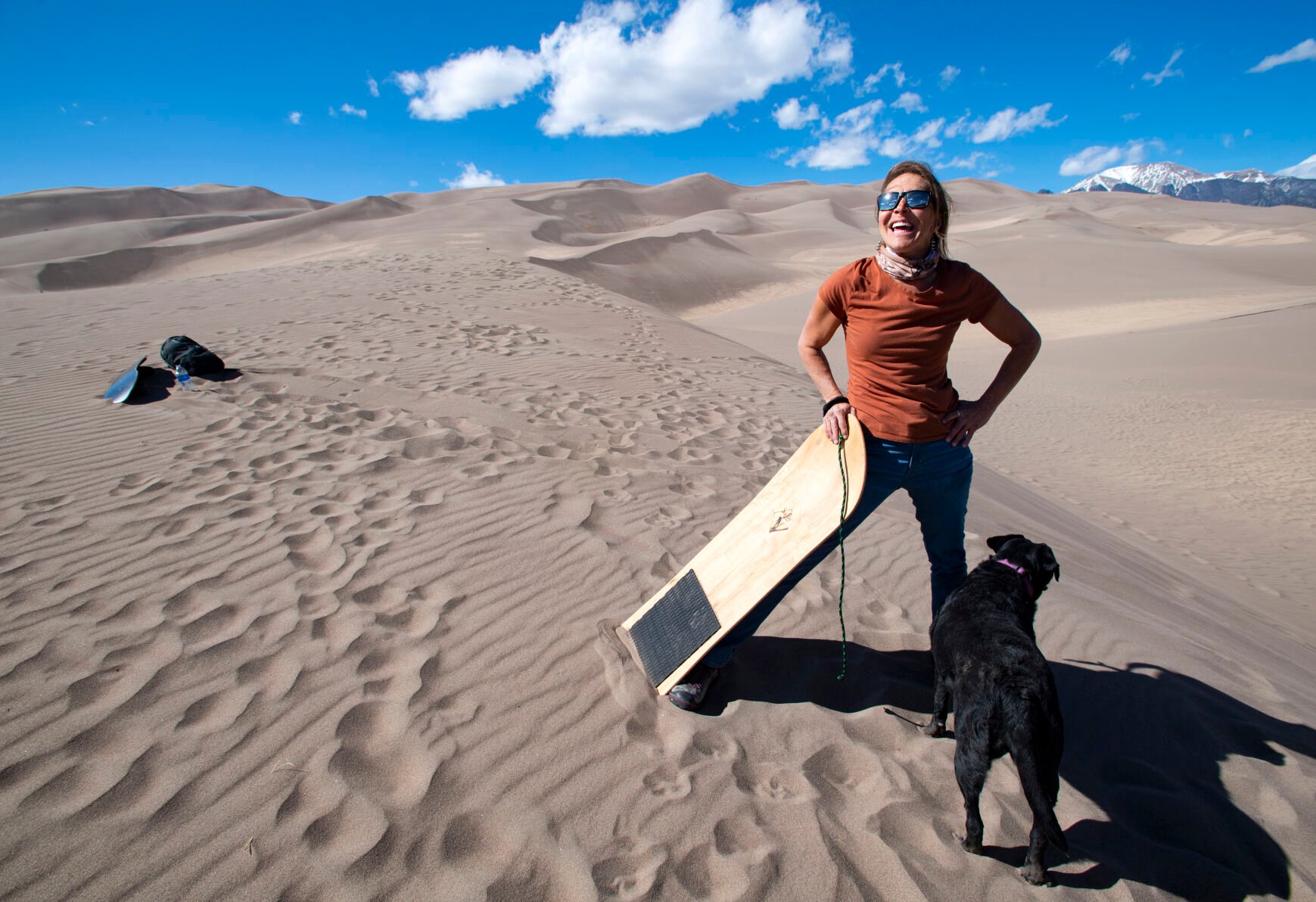 Amy Raney, the owner of SpinDrift SandBoard Rentals in Blanca, is all smiles after climbing the dunes for another ride on her sandboard with her dog Bella Wednesday, April 7, 2021, at the Great Sand Dunes National Park & Preserve outside Mosca, Colo. (The Gazette, Christian Murdock) (Christian Murdock/The Gazette)