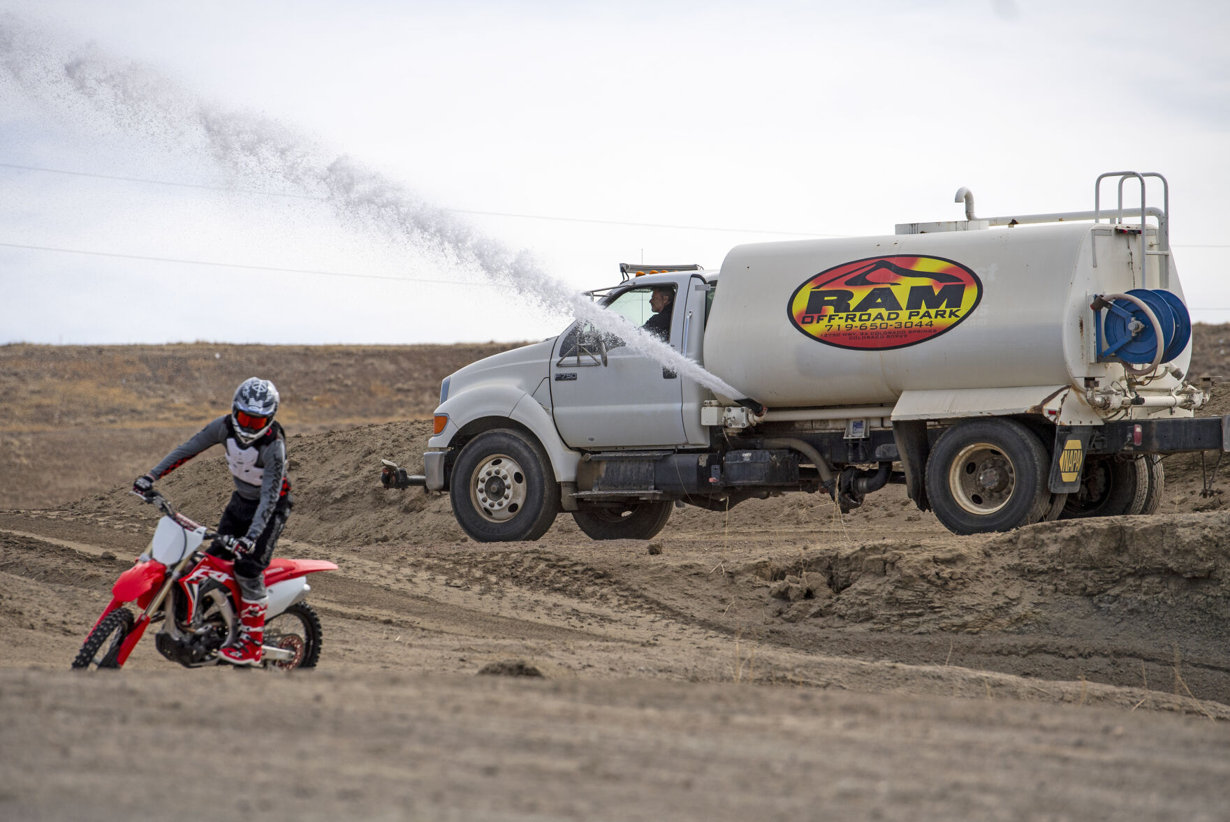 Ray Mandel, owner of RAM Off-Road Park, sprays the kids track with water. Watering the track is a regular part of the maintenance Mandel has to do. (Parker Seibold, The Gazette)