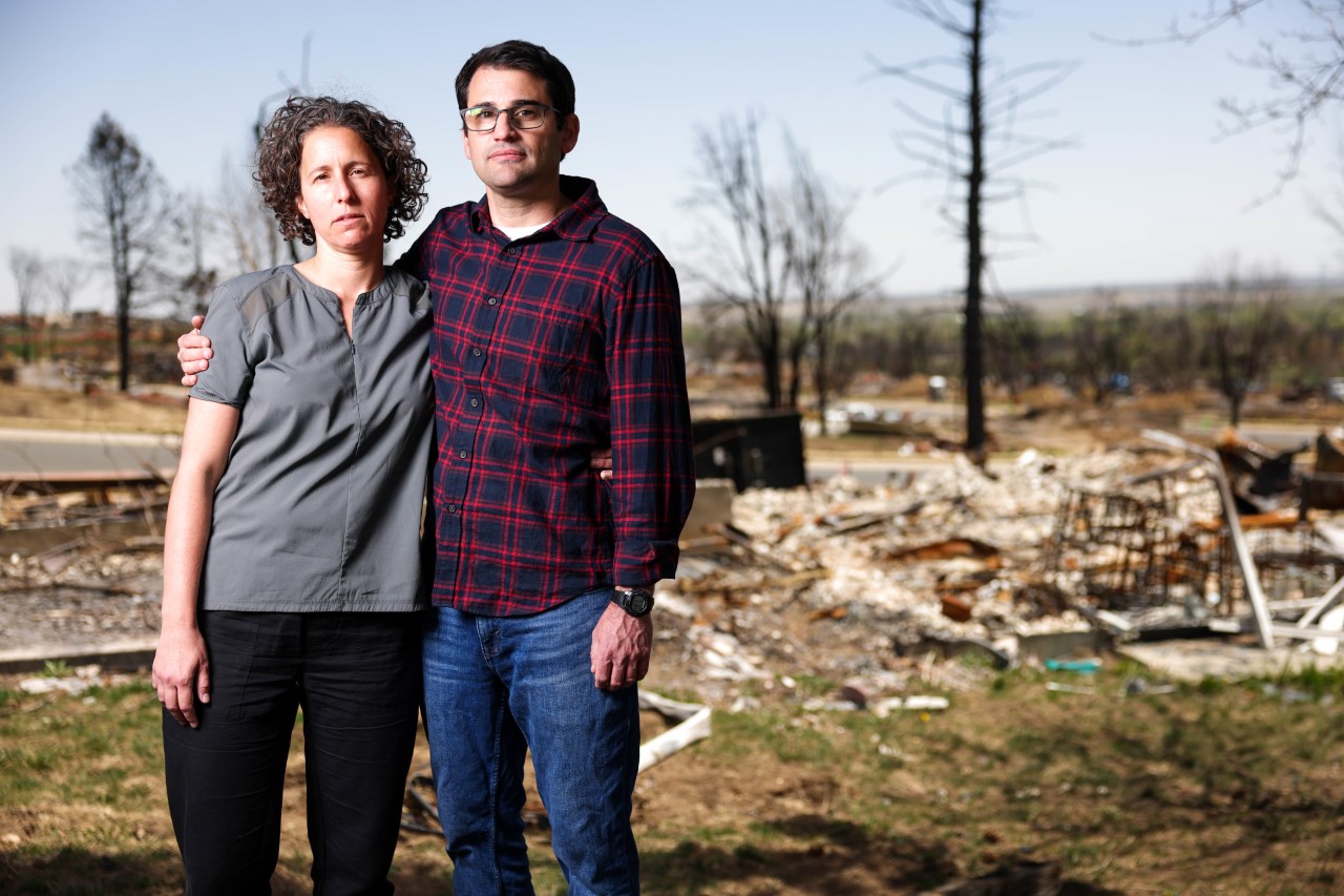 Rona Schank, left, and her husband, Amit Ginsburg, stand next to the ruins of their burned home on Monday, May 9, 2022, in Louisville. Schank and Ginsburg lost their home during the Marshall fire, the most destructive fire in Colorado history. (Michael Ciaglo/Special to The Denver Gazette)