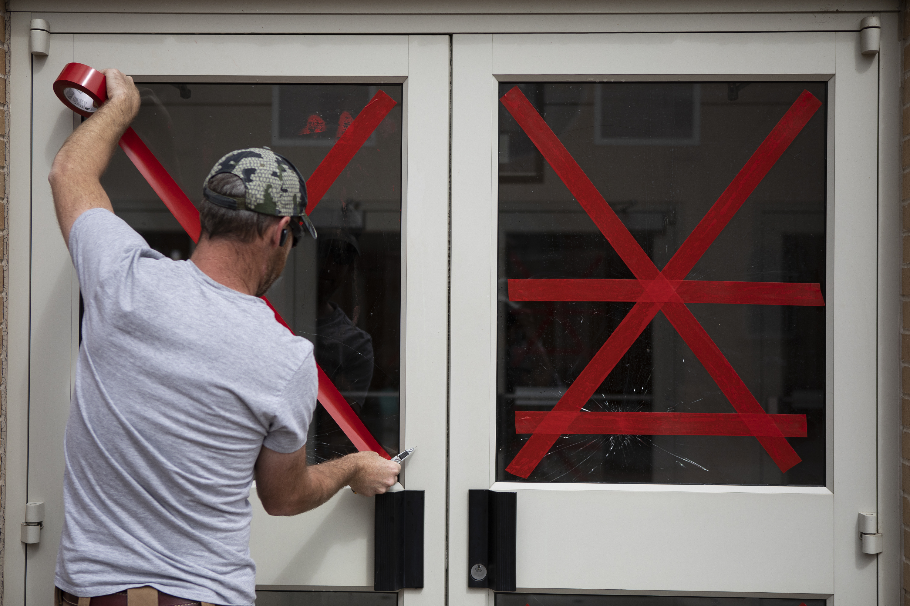 Andrew Neitenbach with Horizon West Builders uses tape to stabilize broken glass doors at Sacred Heart of Mary Catholic Parish on Wednesday, May 4, 2022, in Boulder, Colo. Beyond the broken windows, the church had multiple exterior walls and statues spray painted the night before. (Timothy Hurst/The Denver Gazette) (Timothy Hurst)