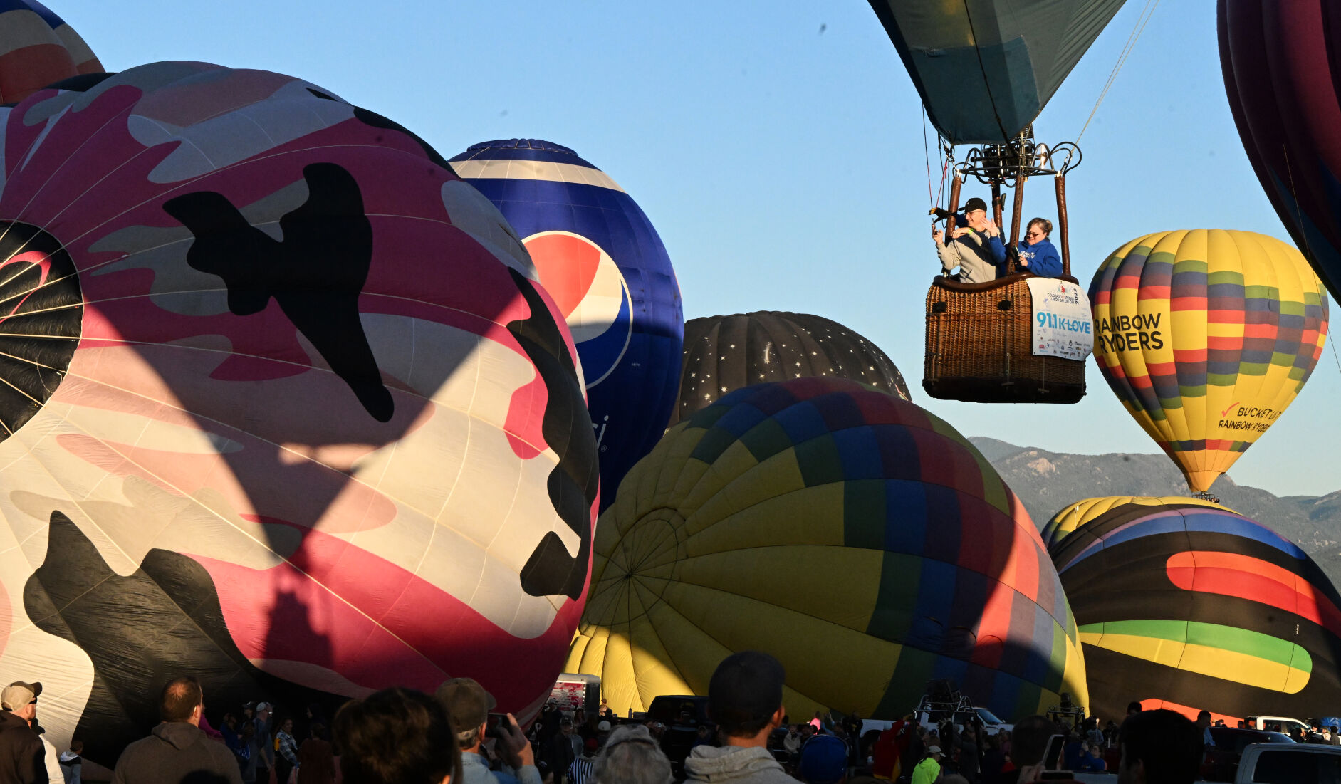 The second wave of balloons inflates and get ready to take to the air as a balloon dips in Prospect Lake on the second day of the Labor Day Liftoff on Sunday, Sept. 4, 2022. (Photo by Jerilee Bennett, The Gazette) (Jerilee Bennett)