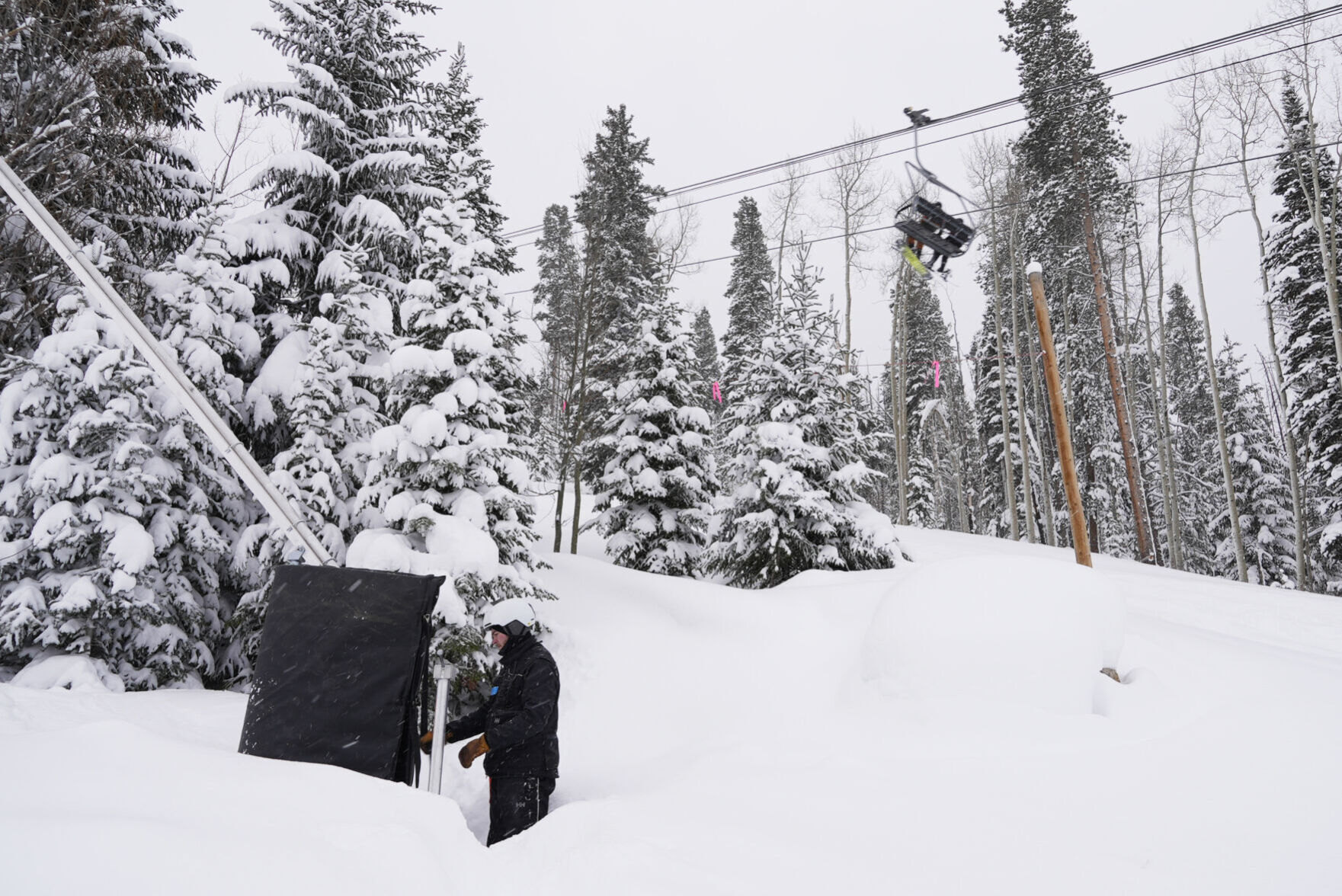 Ian Sidwell adjusts a machine used to make snow at Vail Mountain Resort on Dec. 29 as snowboarders ride a lift. The company says it is in need of housing for employees and is asking a judge to overturn an “emergency ordinance” passed by the town of Vail blocking a new project. (Associated Press file)