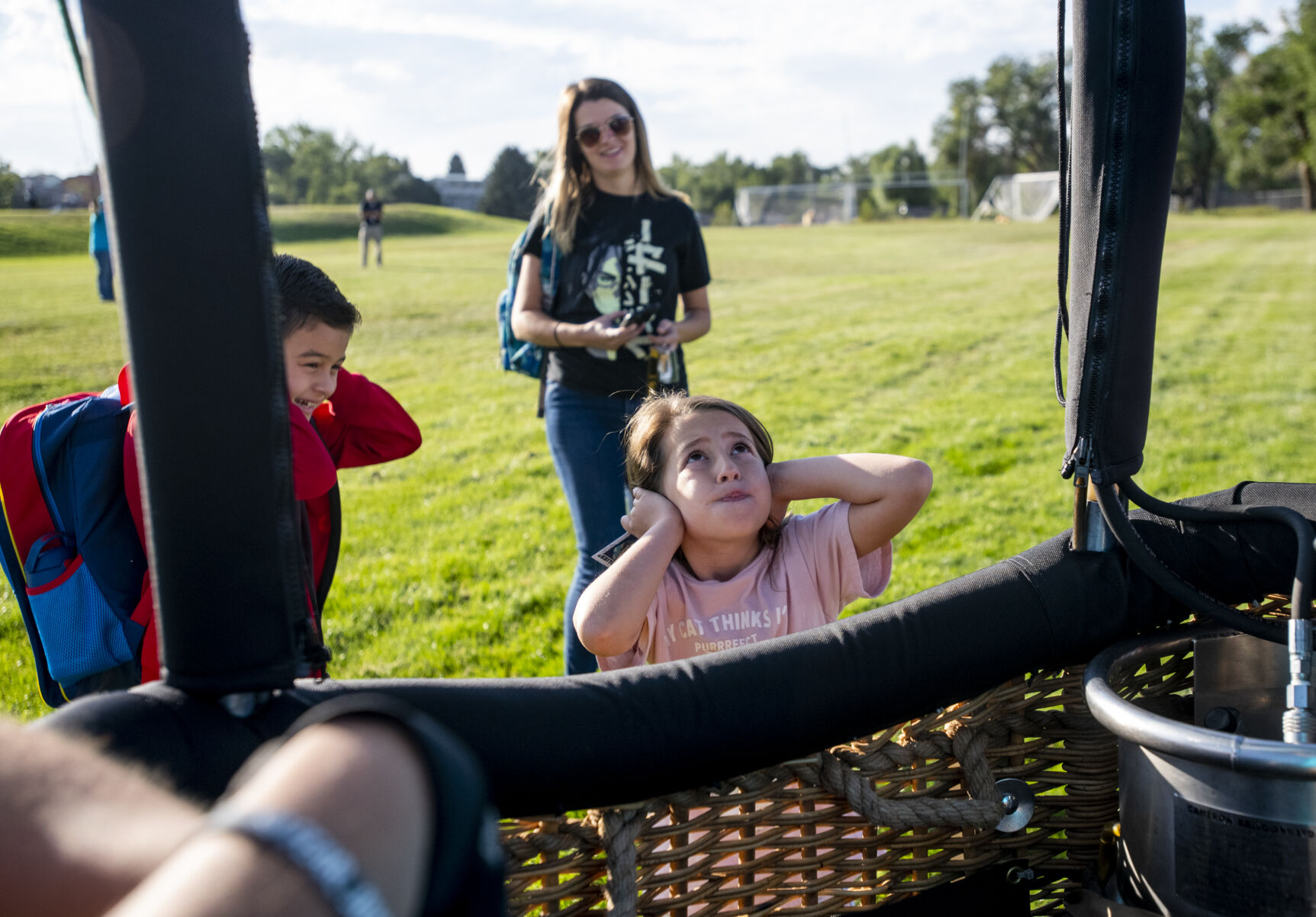 Kids cover their ears as a burner inflates a hot air balloon after landing in a school athletic field on Friday, Sept. 2, 2022. (Parker Seibold / The Gazette) (Parker Seibold/ The Gazette)