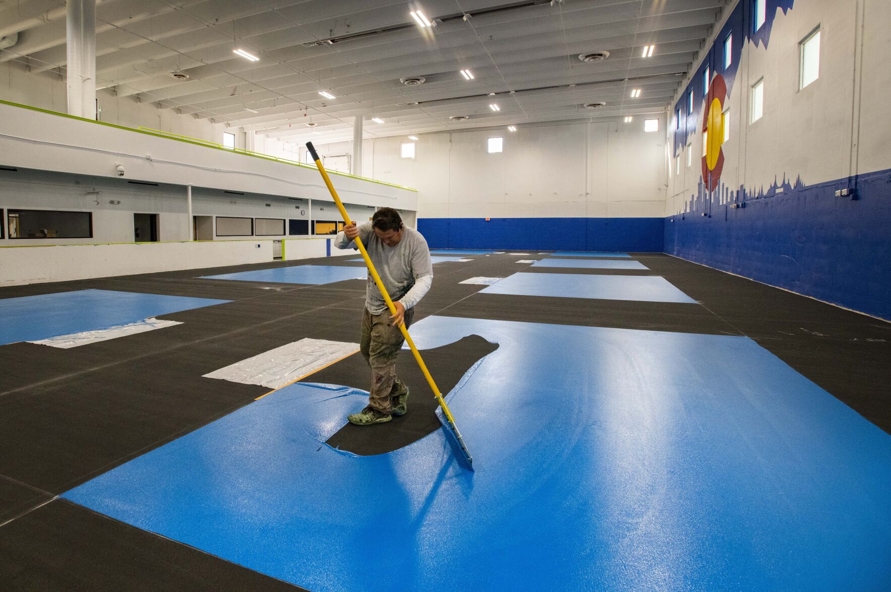 Altitude Athletic Surface worker Ron Alexander spreads paint on one of the eight pickleball courts at the new Springs Pickleball Tuesday, Sept. 19, 2022. The indoor pickleball facility opens Saturday, Oct. 1, at the former Trampoline World in Colorado Springs. (The Gazette, Christian Murdock) (Christian Murdock)