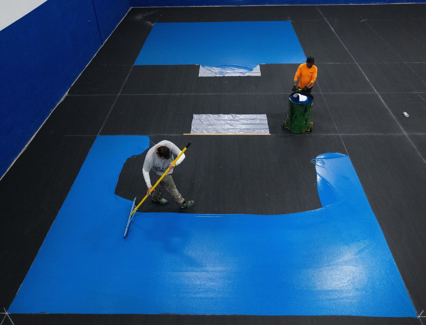 Altitude Athletic Surface worker Ron Alexander spreads paint on one of the eight pickleball courts at the new Springs Pickleball Tuesday, Sept. 19, 2022, while his co-worker Jesus Hernandez waits to pour more paint. The indoor pickleball facility opens Saturday, Oct. 1, at the former Trampoline World in Colorado Springs. (The Gazette, Christian Murdock) (Christian Murdock)