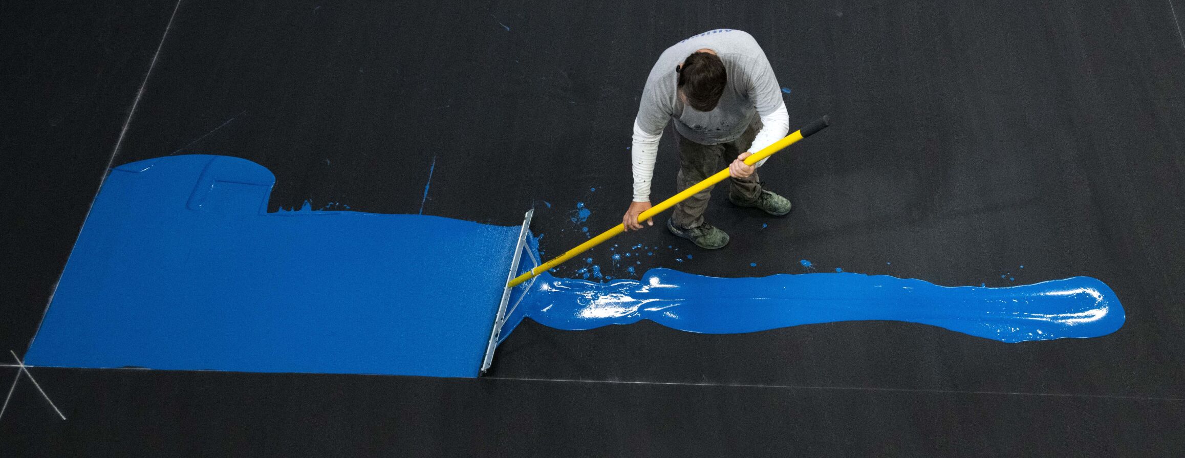 Altitude Athletic Surface worker Ron Alexander spreads paint on one of the eight pickleball courts at the new Springs Pickleball Tuesday, Sept. 19, 2022. The indoor pickleball facility opens Saturday, Oct. 1, at the former Trampoline World in Colorado Springs. (The Gazette, Christian Murdock) (Christian Murdock)