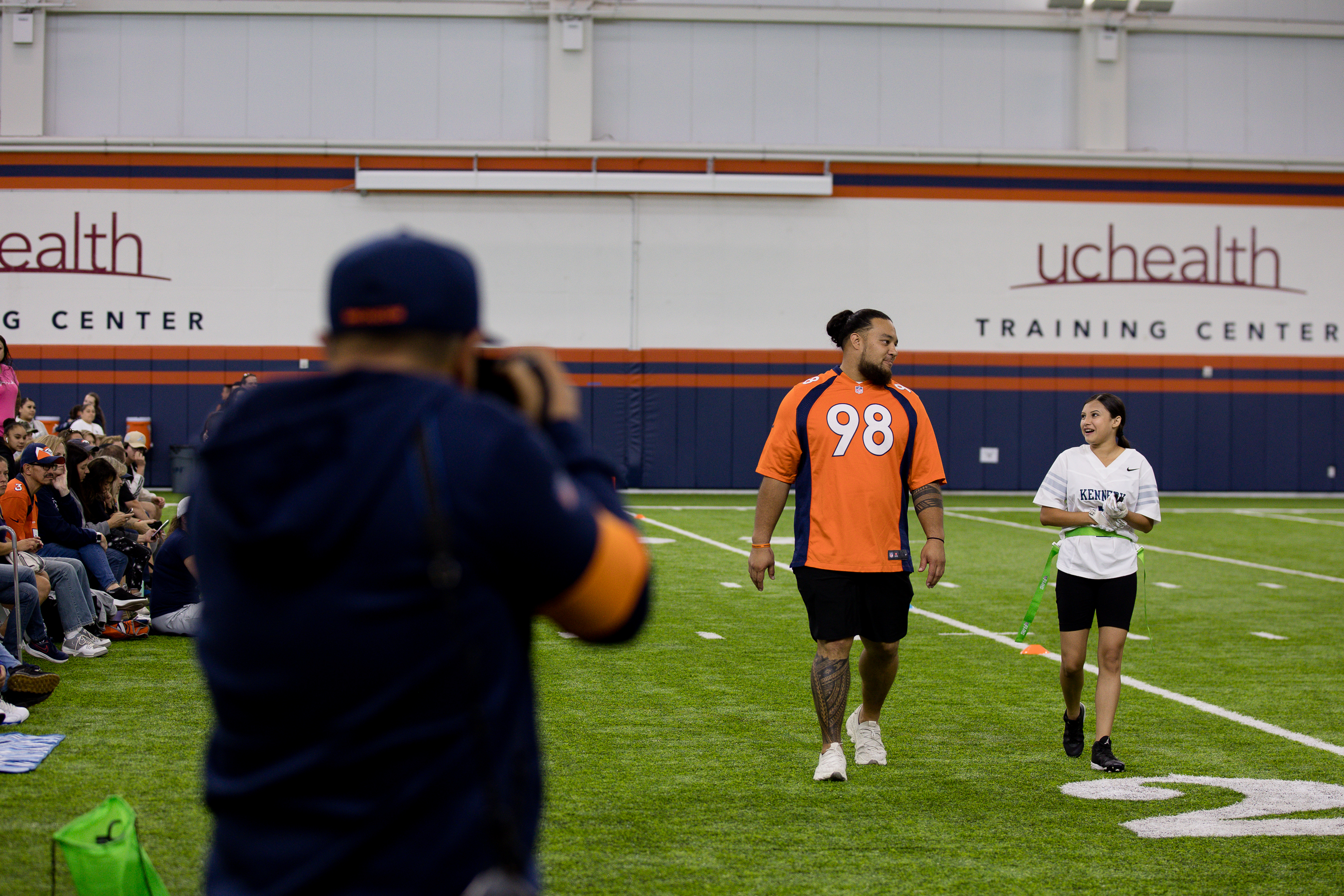 Denver Bronco Michael Purcell walks with a Kennedy High School player on the sidelines Saturday during the Girl's High School Flag football Championship tournament. (Sara Hertwig/for The Denver Gazette)
