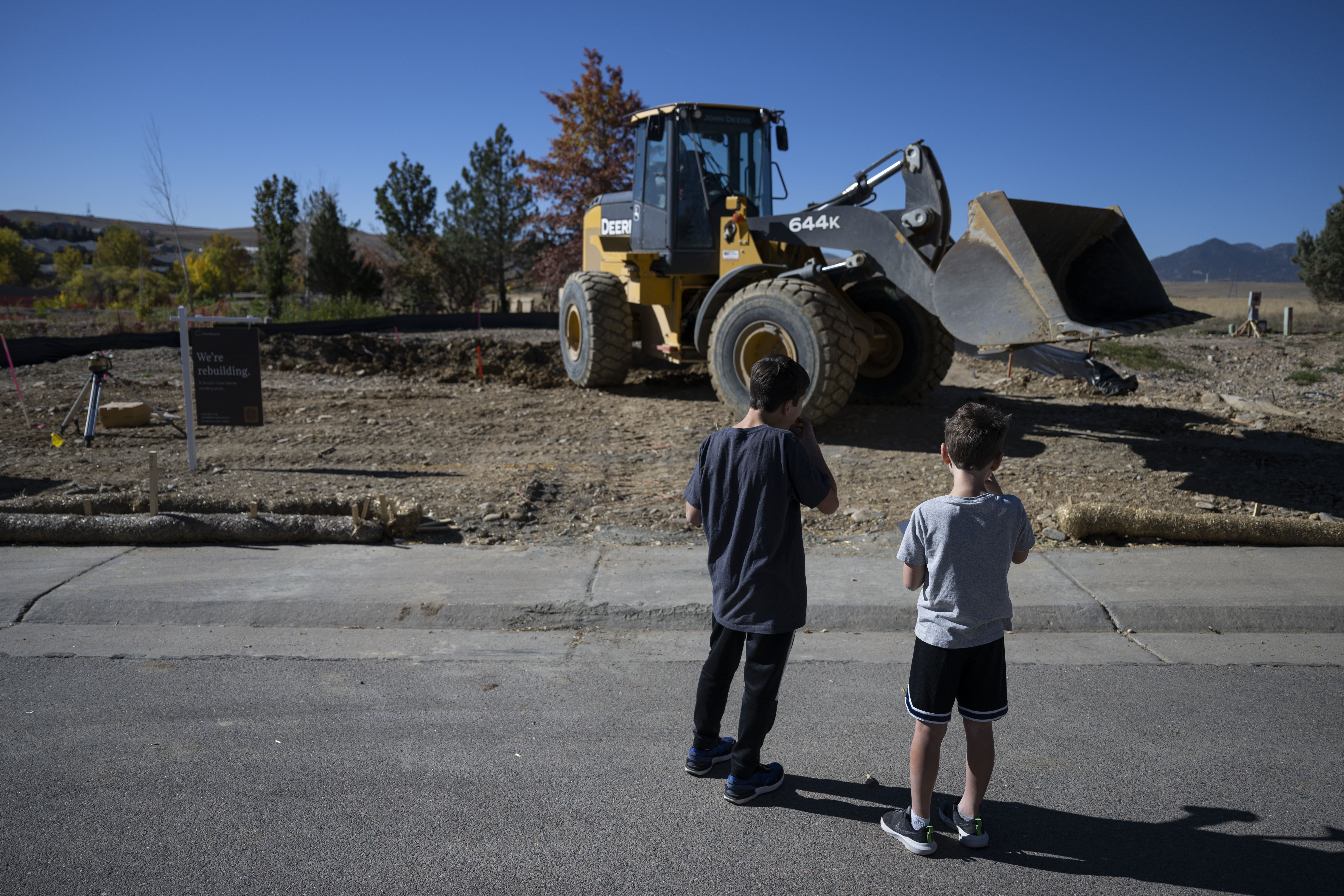 Brothers Nathan, 14, and Collin Cheek, 8, eat donuts provided by the construction crew as they watch a bulldozer excavate their family’s property to begin rebuilding their home lost in the 2021 Marshall Fire, on Wednesday, Oct. 19, 2022, in Superior, Colo. (Timothy Hurst/The Gazette) (TimHursttim.hurst@gazette.comhttps://secure.gravatar.com/avatar/aca82bd62b4ee425c598527cd6faa1b1?d=mm&r=g)