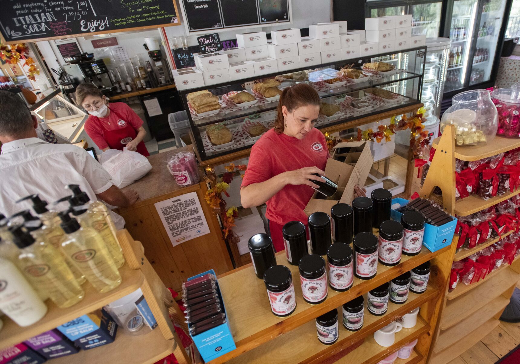 General manager Amanda Schaal stocks the shelves with cherry tea while Gloria Sherman helps a customer at the Lyons location of Colorado Cherry Co. (Christian Murdock/The Gazette)