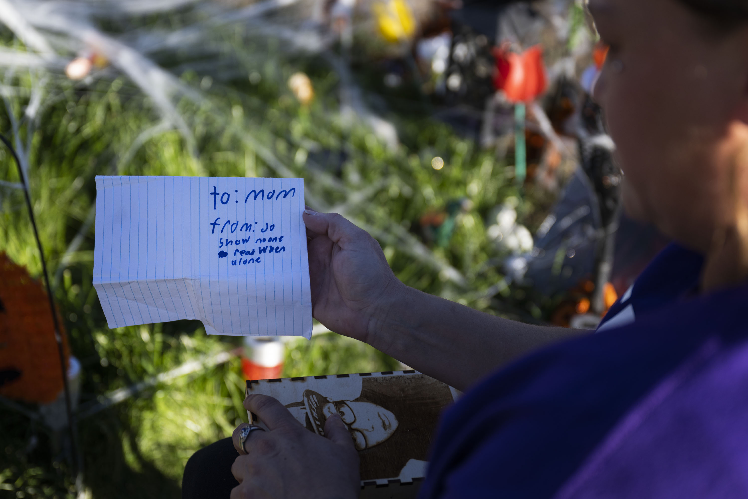 Christina Luna, the mother of Josiah Velasquez, pulls the last note that Josiah left for her before passing away from a fentanyl overdose while visiting his grave with her close friend and sister Tara Garcia on Thursday, Oct. 20, 2022, at the Crown Hill Cemetery in Lakewood, Colo. Luna and Garcia visit the site often and bring a large photo of Josiah with them each time they visit. (Timothy Hurst/The Gazette) (TimHursttim.hurst@gazette.comhttps://secure.gravatar.com/avatar/aca82bd62b4ee425c598527cd6faa1b1?d=mm&r=g)