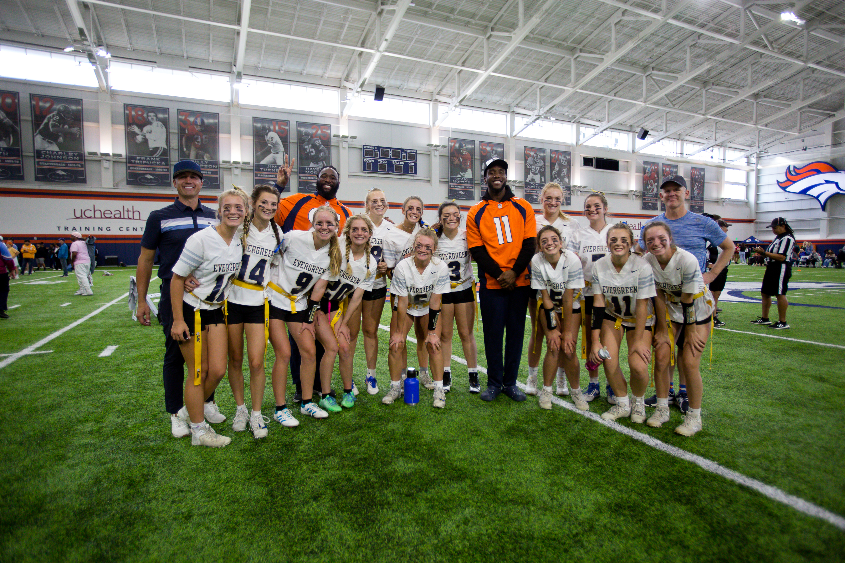 The Evergreen High School team pose with Broncos players after winning the first game in the Girl's High School Flag football Championship tournament Saturday. (Sara Hertwig/for The Denver Gazette) (Sara Hertwig)