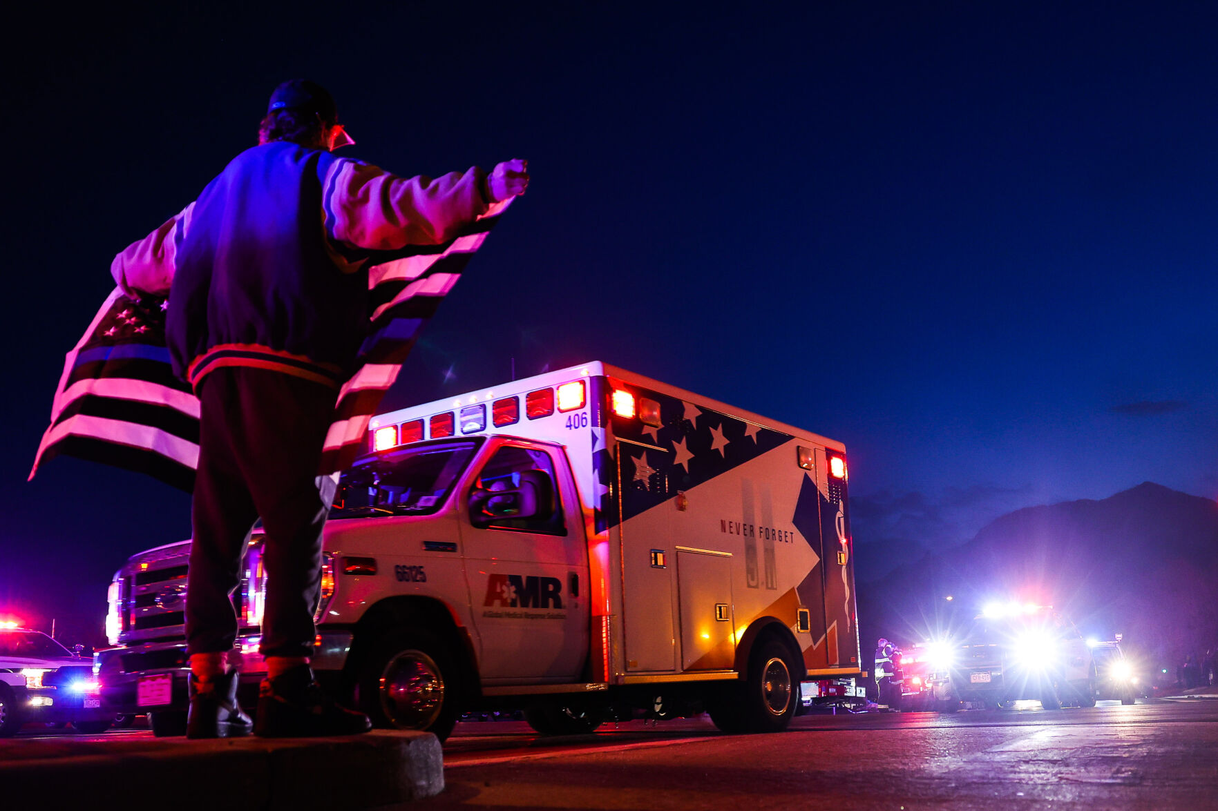 A man holds a thin blue line flag as emergency vehicles escort the body of a slain police officer from the scene of a shooting at a King Soopers on Monday, March 22, 2021 in Boulder. Ten people were killed in the shooting. (Michael Ciaglo/Special to The Denver Gazette) (Michael Ciaglo/Special to The De)