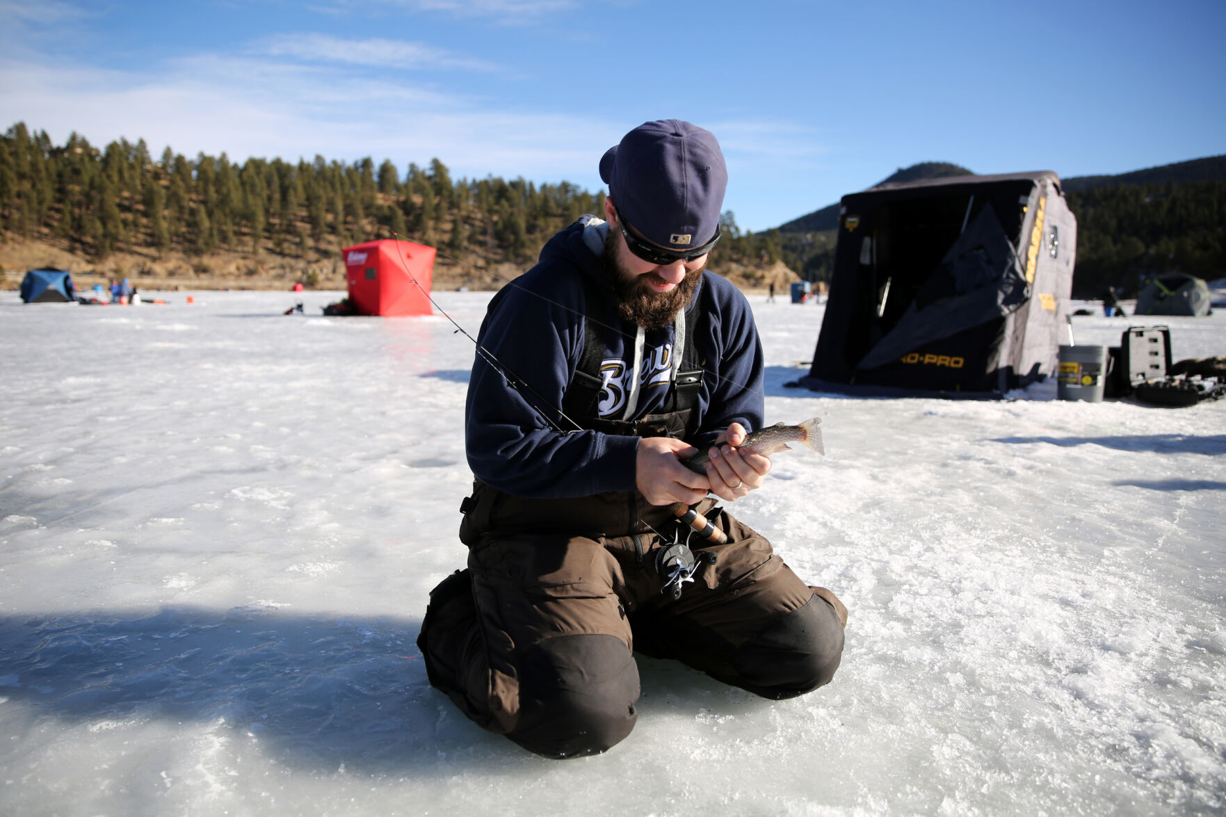 Ernie Schnook works on getting a grip on a rainbow trout he just caught while ice fishing with some friends at Evergreen Lake on Dec. 26, 2020. (Forrest Czarnecki/The Gazette) (Forrest Czarnecki)