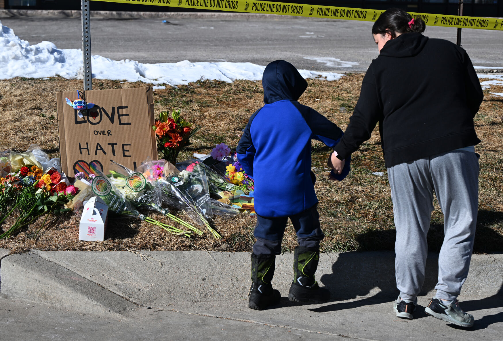 Kristen Morris and her son, Kai Morris, 6, walk away from a memorial Sunday morning, Nov. 20, 2022, for the victims of a shooting at Club Q in Colorado Springs Saturday night. Five people died and 25 were injured in the shooting about midnight. Morris wanted to share kindness and she and her two sons placed painted crosses on the memorial. (The Gazette, Christian Murdock) (Christian Murdock/The Gazette)