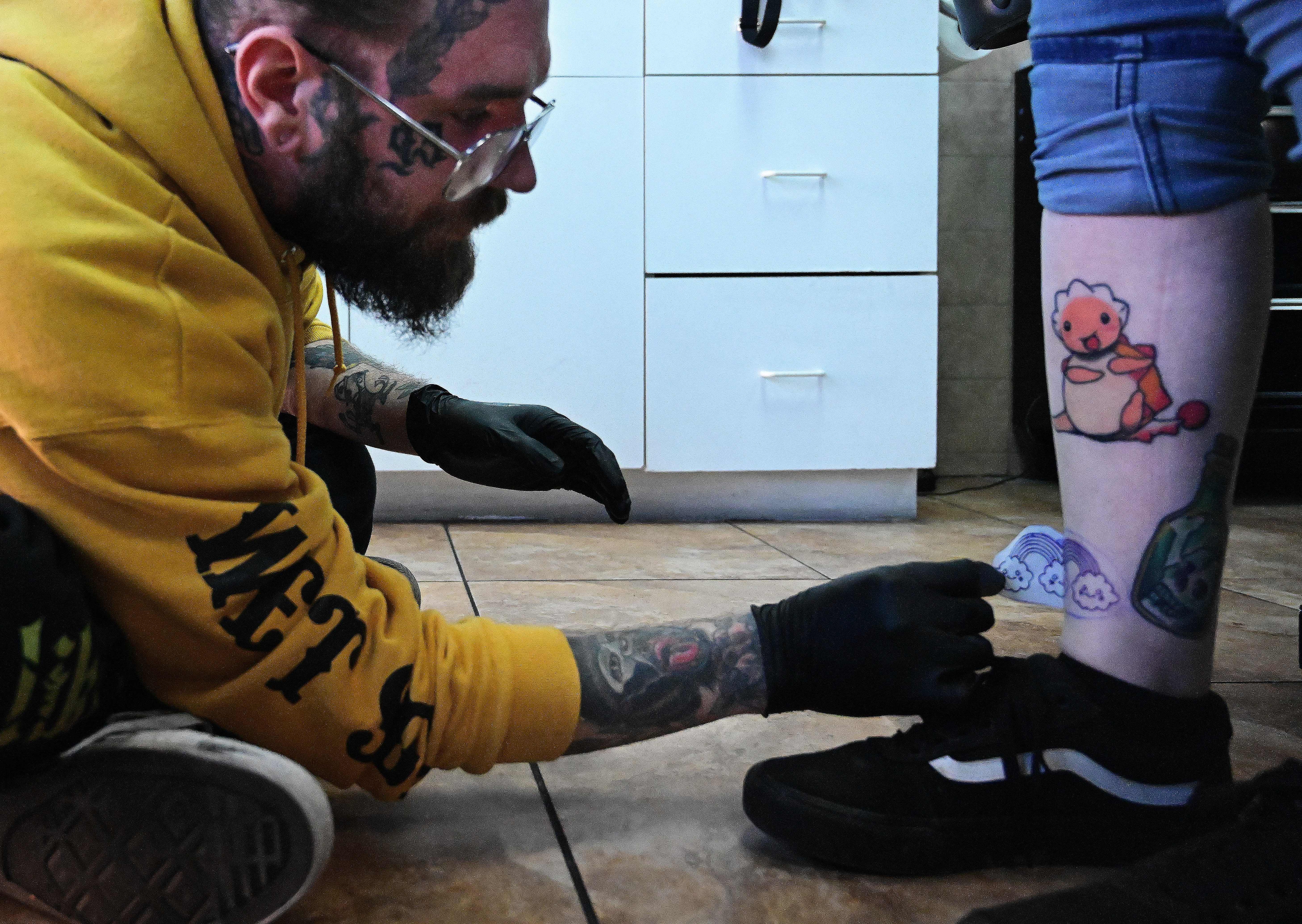Zach Krueger puts a stencil of a rainbow “pride” tattoo on the leg of a customer at West Side Tattoo as a part of a fundraiser for the victims of the Club Q shooting. Tuesday, Nov. 22, 2022. (Photo by Jerilee Bennett, The Gazette)