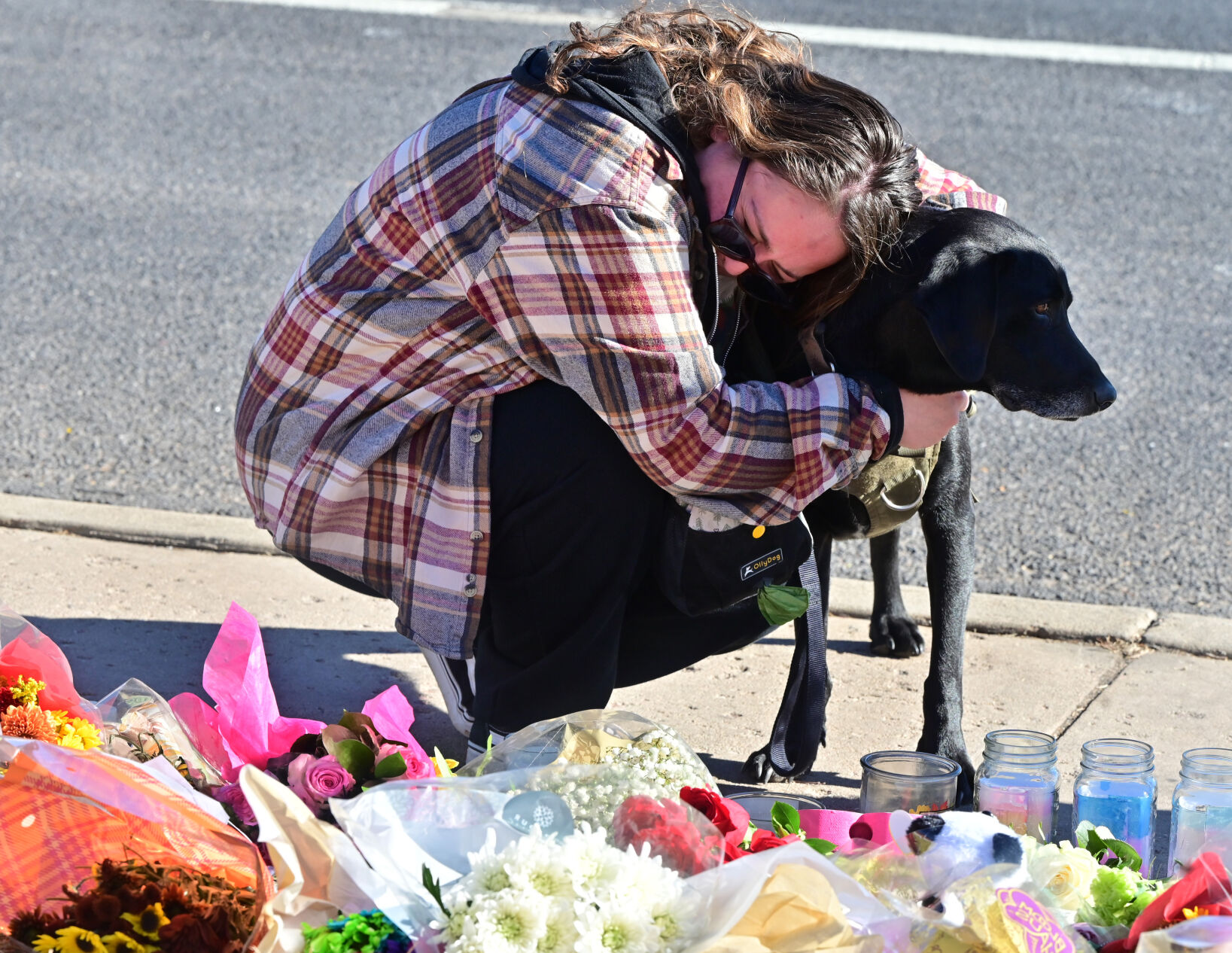 Haley Turner hugs her dog, Oliver, at the scene of a memorial of flowers and sentiments for the five people who were killed at Club Q on Saturday night. Turner is a regular at the club and spent yesterday morning calling all of her friends to find out that they were okay. Monday, Nov. 21, 2022. (Photo by Jerilee Bennett, The Gazette)