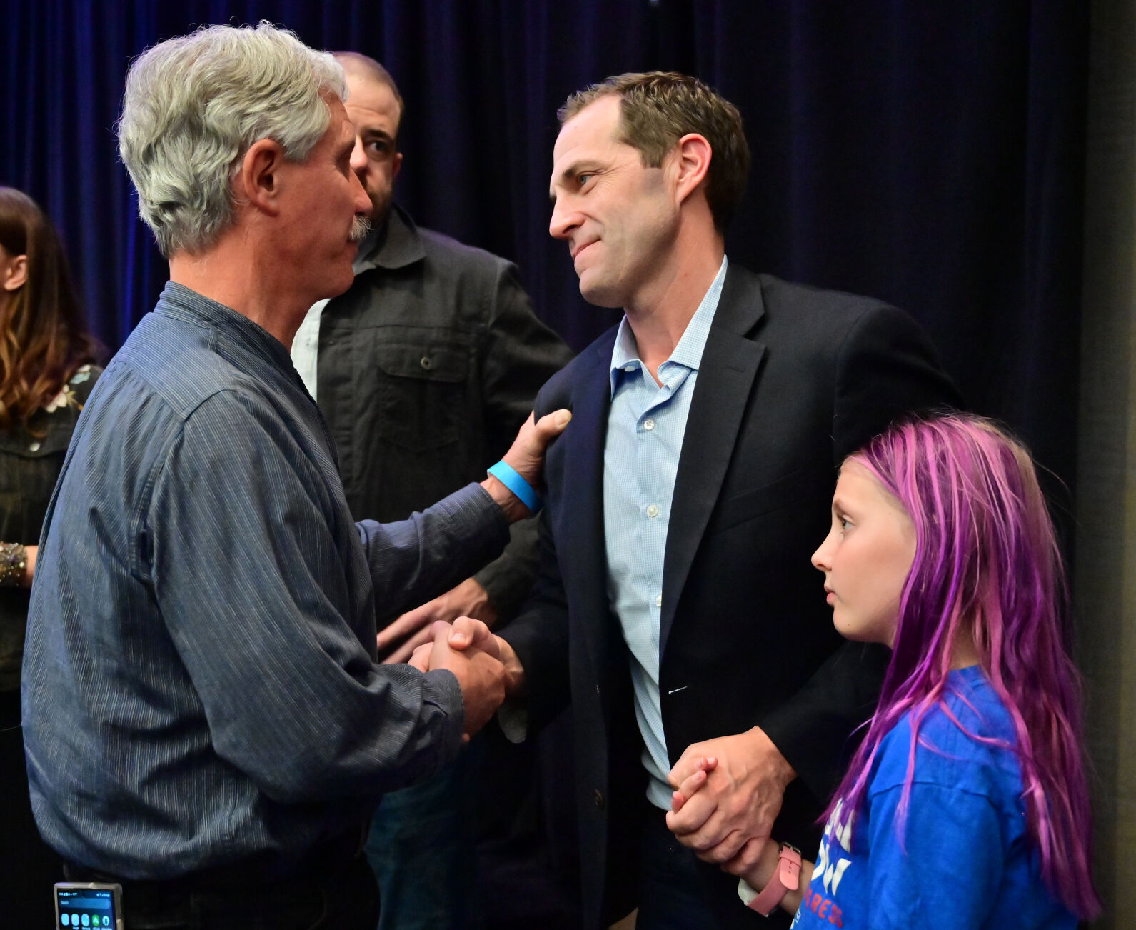 U.S. Rep. Jason Crow gets congratulations from supporter John Powers while he hold the hand of his daughter, Josephine Crow, after giving his victory speech at the Democratic watch party on Tues., Nov. 8, 2022. (Photo by Jerilee Bennett, The Gazette)