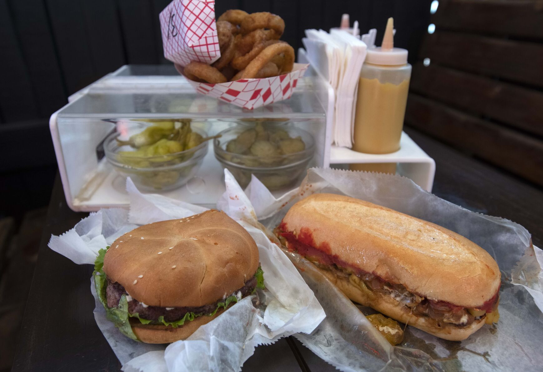 A jalapeño cream cheese burger, left, and a sweet Italian Swiss sandwich with onion rings and condiments at My Brother’s Bar in Denver. (Christian Murdock, The Gazette)