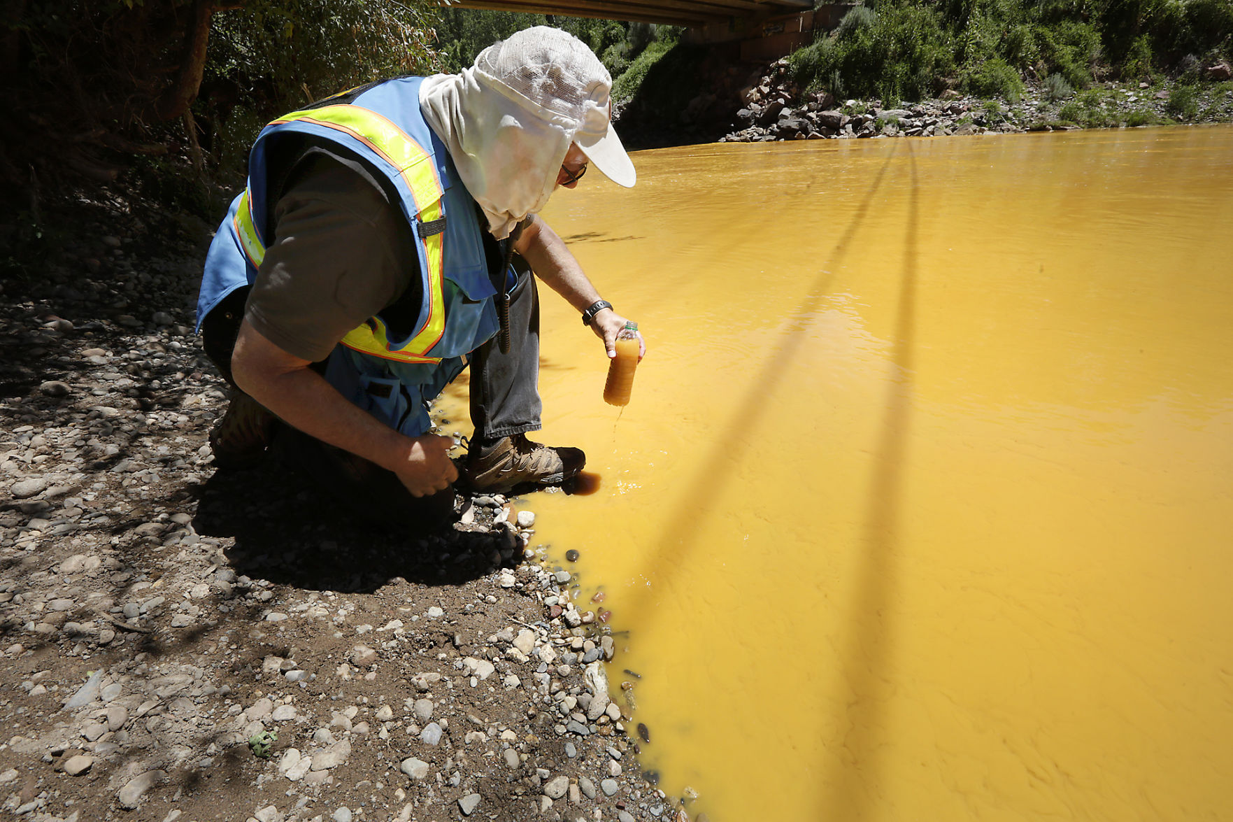 In this August 2015 file photo, Dan Bender, with the La Plata County Sheriff's Office, takes a water sample from the Animas River near Durango, Colo. after the accidental released of an estimated 3 million gallons of waste from the Gold King Mine by a crew led by the Environmental Protection Agency. The EPA says it has almost finished reviewing hundreds of damage claims from the spill, but the agency has still not released a clear accounting of the claims made for economic losses and personal injuries. (JERRY MCBRIDE/THE DURANGO HERALD VIA AP)