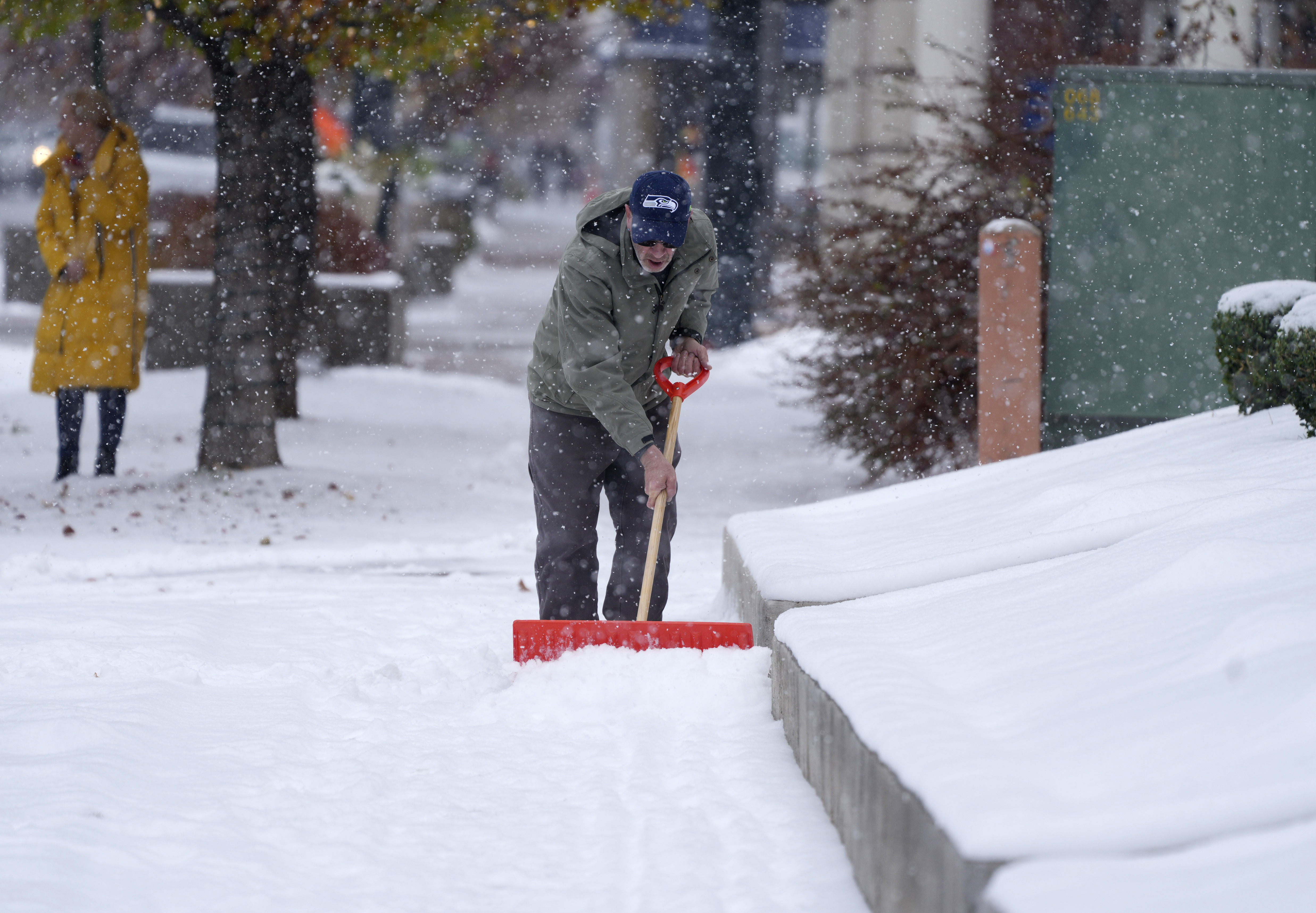 A Denver homeowner cleared snow from a walkway after a cold front packing subfreezing temperatures and light snow swept over the intermountain West Thursday, Nov. 17, 2022, in Denver. Forecasters predict that the cold temperatures will persist through Friday before relenting Saturday to more seasonal daytime highs. (DAVID ZALUBOWSKI/THE ASSOCIATED PRESS)