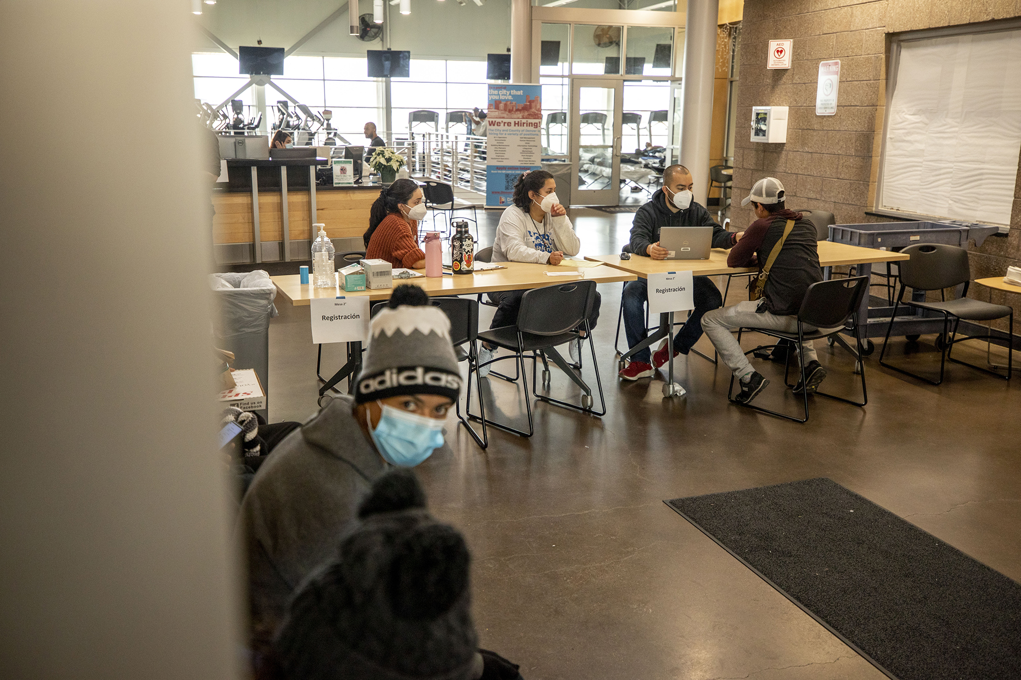 City workers check people into an emergency shelter for people arriving from the southern U.S. border set up at a Denver rec center. Dec. 13, 2022. (Kevin J. Beaty/Denverite,Pool) (Kevin J. Beaty/Denverite)