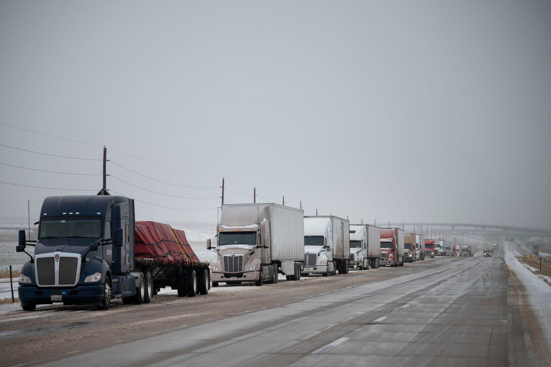 Semis line the eastbound shoulder of Interstate 70 just west of Powhaton Road on Tuesday, Dec. 13, 2022, in Aurora, Colo. Blizzard-like conditions caused the Colorado Department of Transportation to close eastbound I-70 from E470 to the Kansas State Line. (Timothy Hurst/The Gazette) (TIMOTHY HURST/THE DENVER GAZETTE)