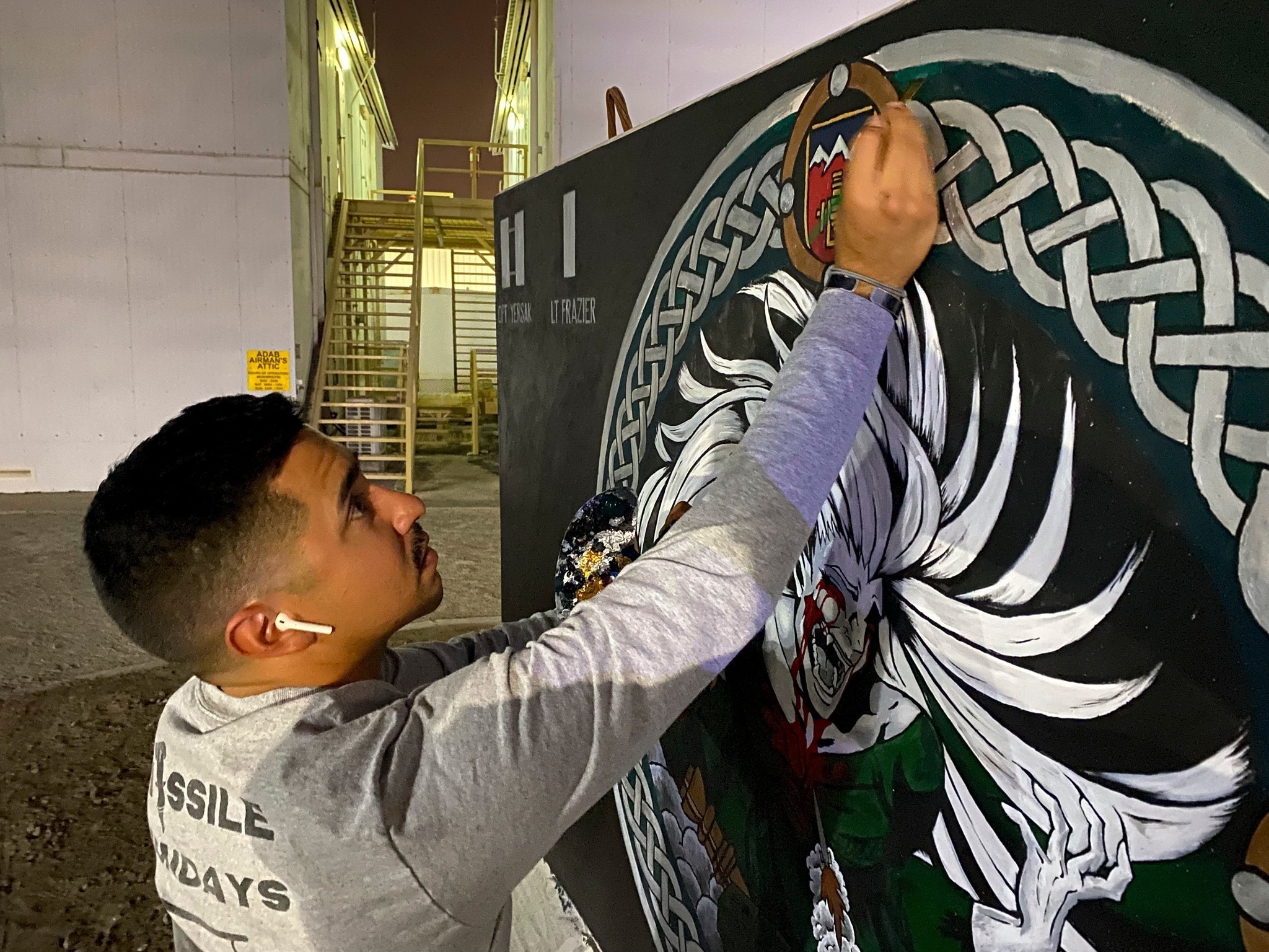 Army Sgt. Anthony Castillo, a mobility specialist assigned to the 3-157th Field Artillery unit and Colorado National Guard, paints a T-Wall with his unit’s adopted patch in April at Al Dhafra Air Base, United Arab Emirates. To avoid temperatures of 120 F or more, Castillo would gather his painting supplies, don a headlamp and begin painting at night. “The Banshee Barricade” took a total of 33 hours over the span of 20 days to finish. (Courtesy of Tech. Sgt. Jeffrey Grossi)