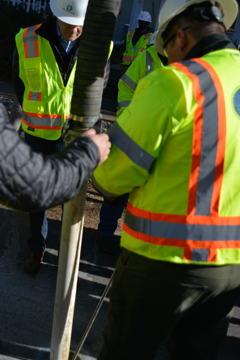 Colorado Sen. Michael Bennet observes AGL Construction workers suctioning dirt out of a 