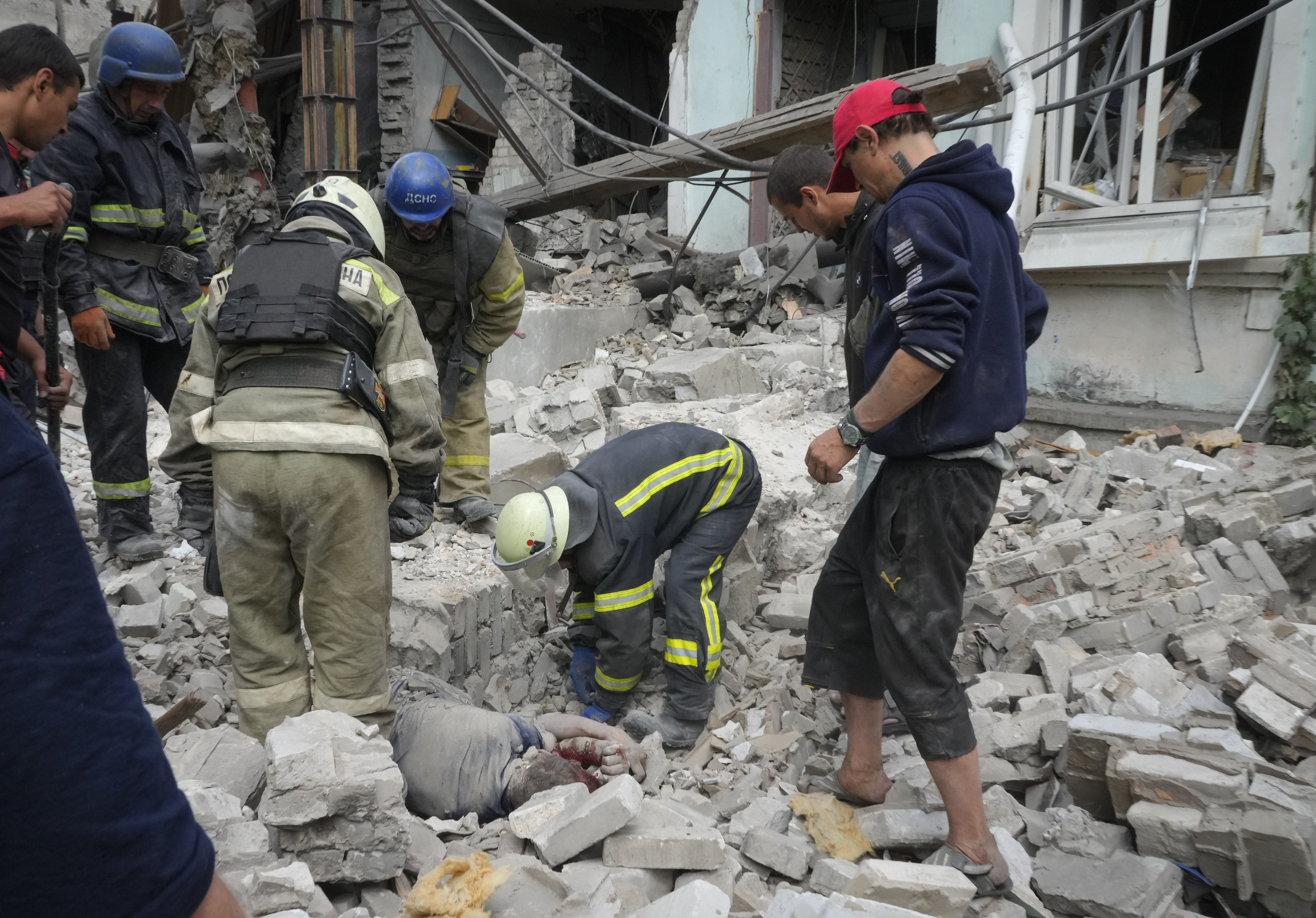 FILE - Search and rescue workers and local residents take a dead body from under the debris of a building after the Russian air raid in Lysychansk, Luhansk region, Ukraine, Thursday, June 16, 2022. (AP Photo/Efrem Lukatsky, File) (Efrem Lukatsky)