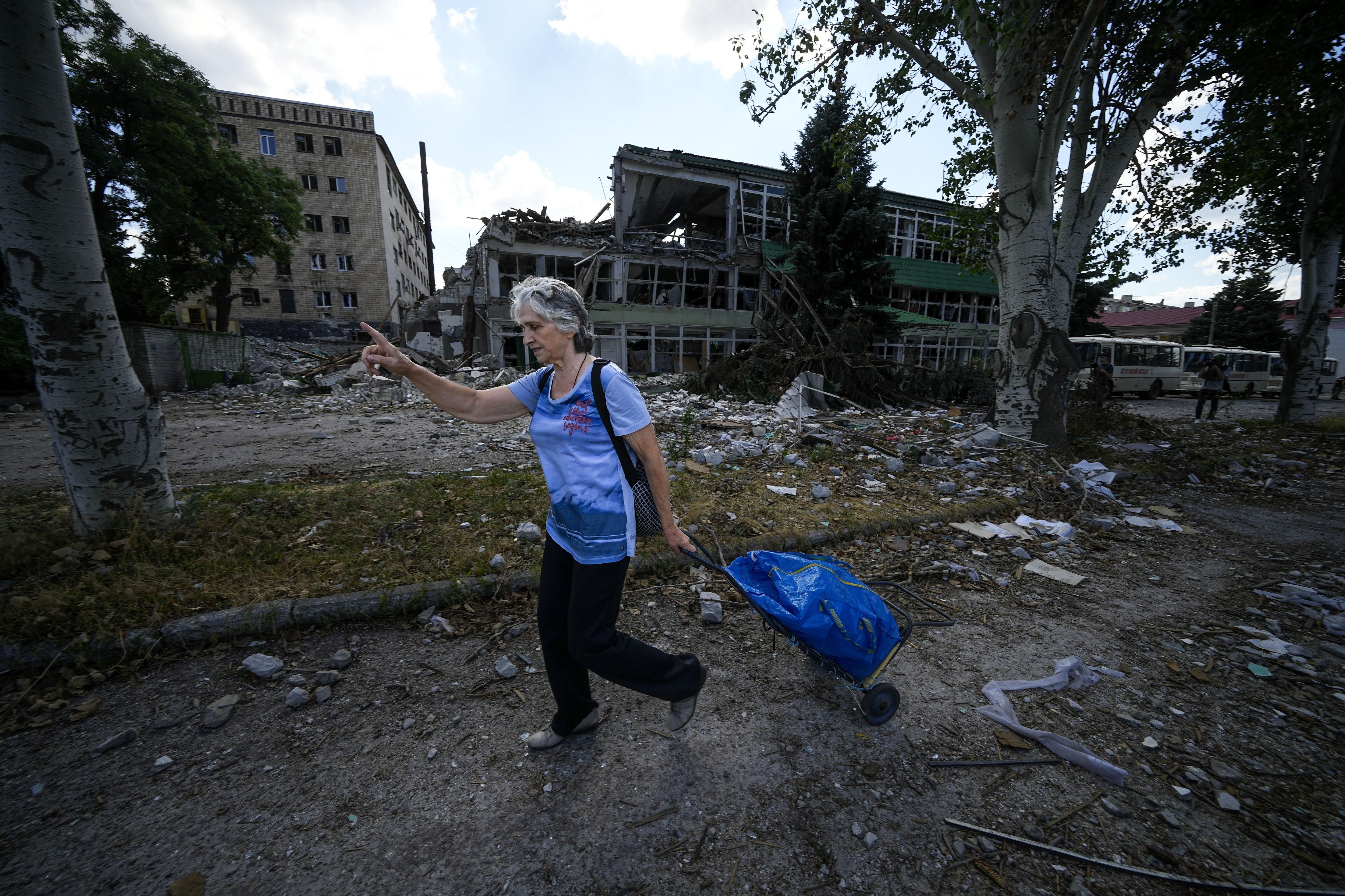 A woman walks past apartment buildings damaged during fighting between Russian and Ukrainian forces in Severodonetsk, in the territory which is under the Government of the Luhansk People's Republic control, in eastern Ukraine, Tuesday, July 12, 2022. This photo was taken during a trip organized by the Russian Ministry of Defense. (AP Photo) (STF)