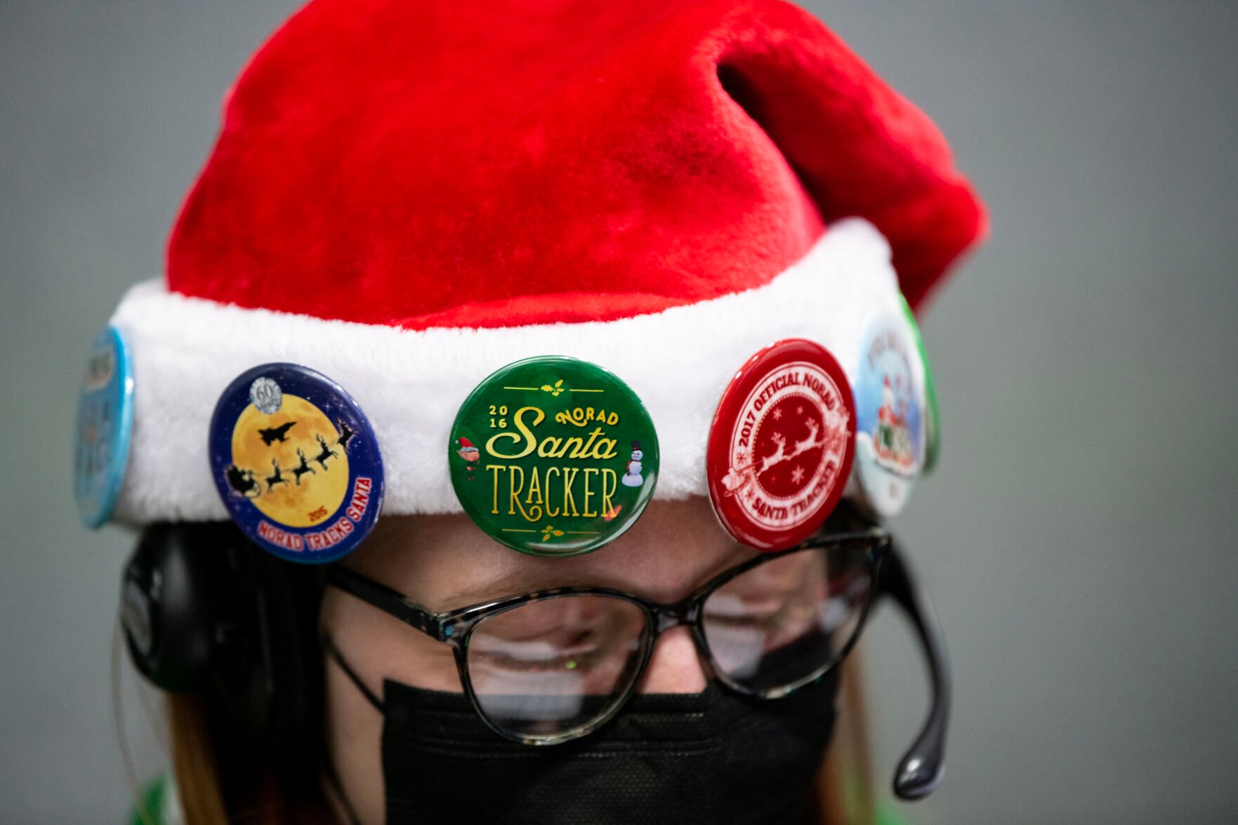 Franziska Reichert wears an array of Santa Tracker pins during her volunteering shift at the NORAD Tracks Santa Operations Center on Christmas Eve. Each year, volunteers work in two hour shifts on Christmas Eve to answer as many as 60,000 calls about Santa’s whereabouts. (The Gazette, Parker Seibold) (Parker Seibold)