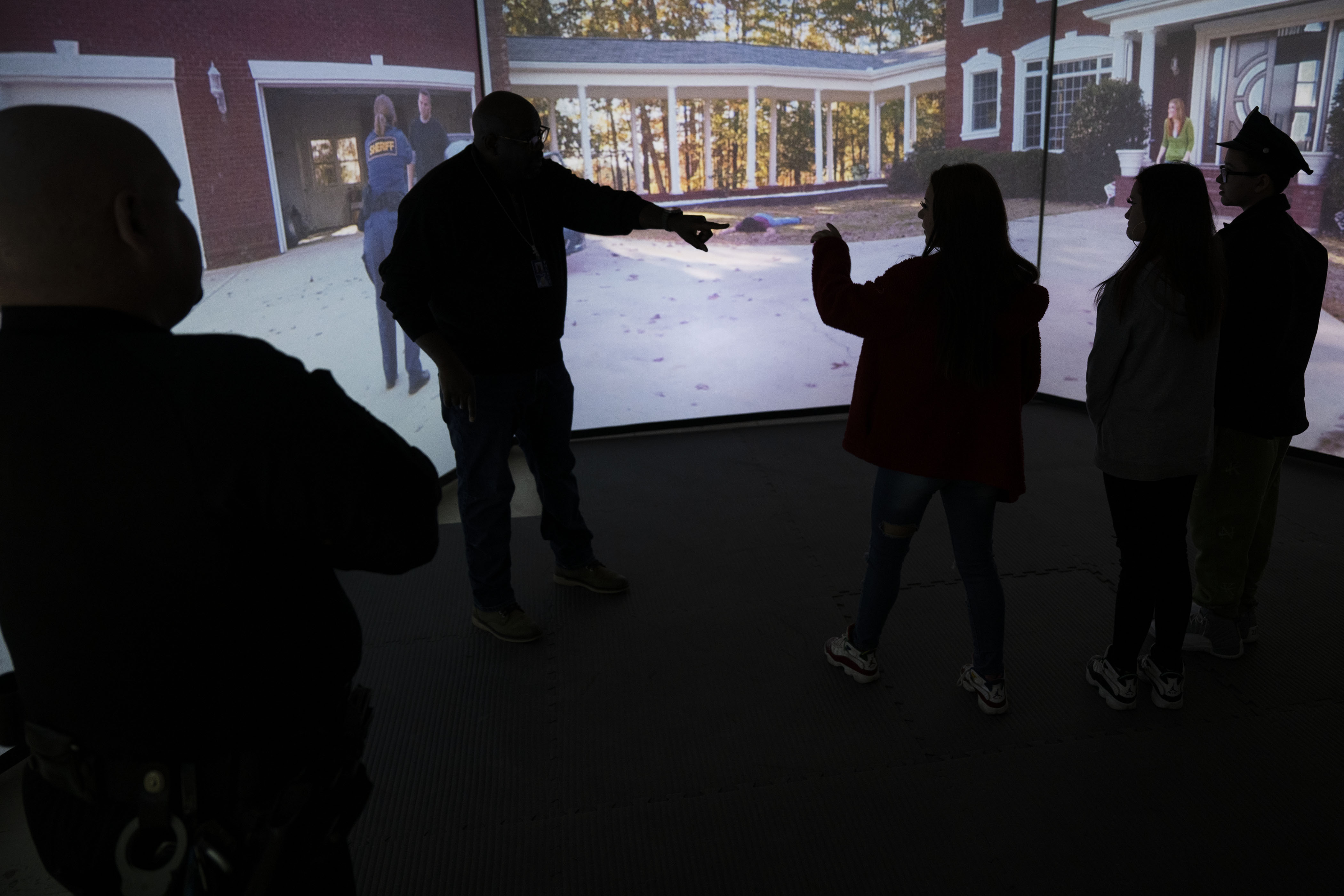 Denver Police technician Tyrone Campbell, center, walks siblings, from right, Kamorin, 14, Kaitlyn, 13, and Lianna, 18, no last names given, through a training simulation at the Denver Police Academy after a simulated ride along for Kamorin on Friday, Dec. 23, at the Denver Police Academy in Denver, Colo. (Timothy Hurst/The Denver Gazette) (TimHursttim.hurst@gazette.comhttps://secure.gravatar.com/avatar/aca82bd62b4ee425c598527cd6faa1b1?d=mm&r=g)