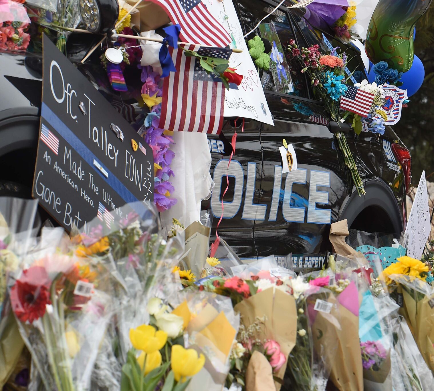 The police cruiser of Officer Eric Talley has almost been swallowed by the flowers and sentiments left at the Boulder Public Safety Center in this March 25, 2021, photo. Talley was among the 10 people who were killed in a shooting at a King Soopers. (Jerilee Bennett, Gazette file)