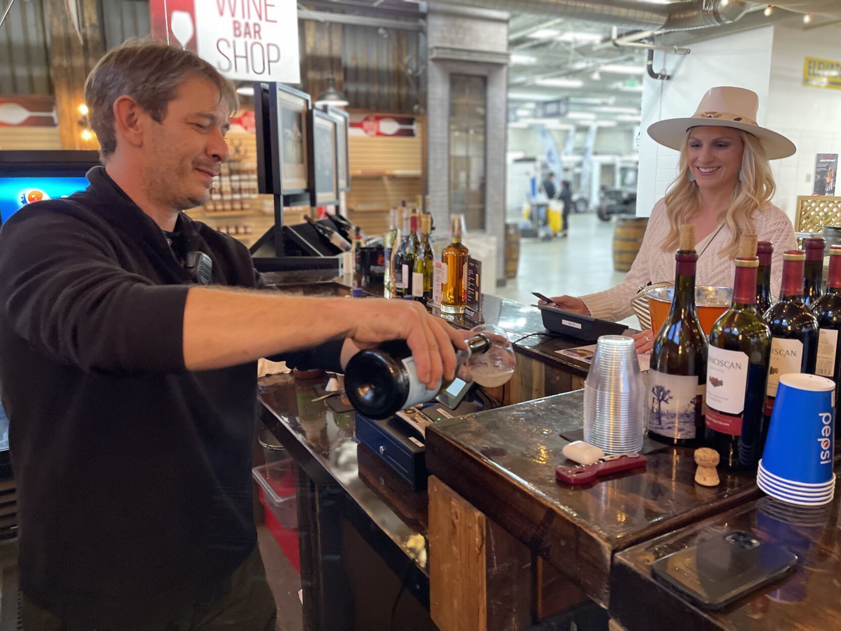 Bartender Matt Stringham pours a glass of wine for Jessica Johnson at the wine bar on Jan. 11, 2023 at the National Western Stock Show. (NICOLE C. BRAMBILA/THE DENVER GAZETTE)