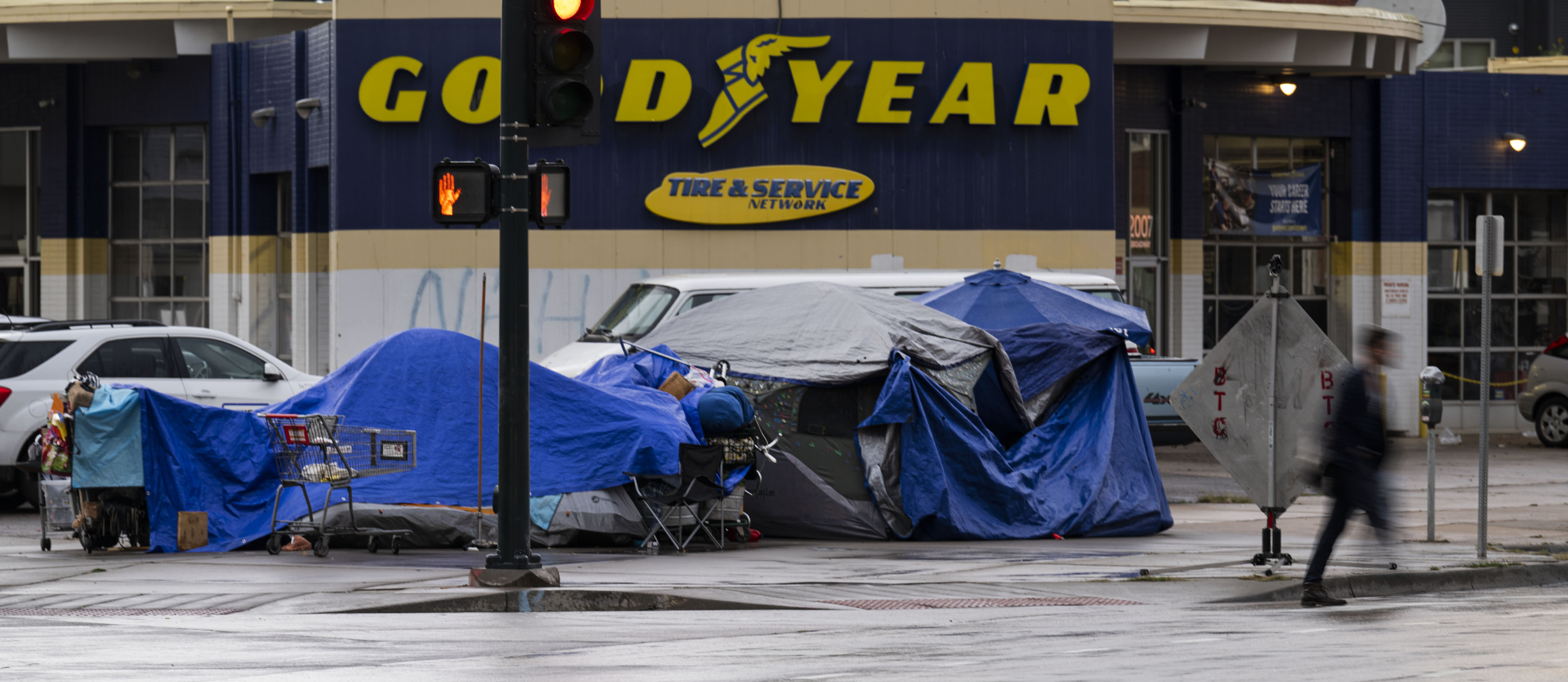 FILE PHOTO: A pedestrian crosses the street in front of an encampment at 20th Street and North Broadway on Wednesday, Sept. 14, 2022, in Denver, Colo. (Timothy Hurst/The Denver Gazette) (TimHursttim.hurst@gazette.comhttps://secure.gravatar.com/avatar/aca82bd62b4ee425c598527cd6faa1b1?d=mm&r=g)