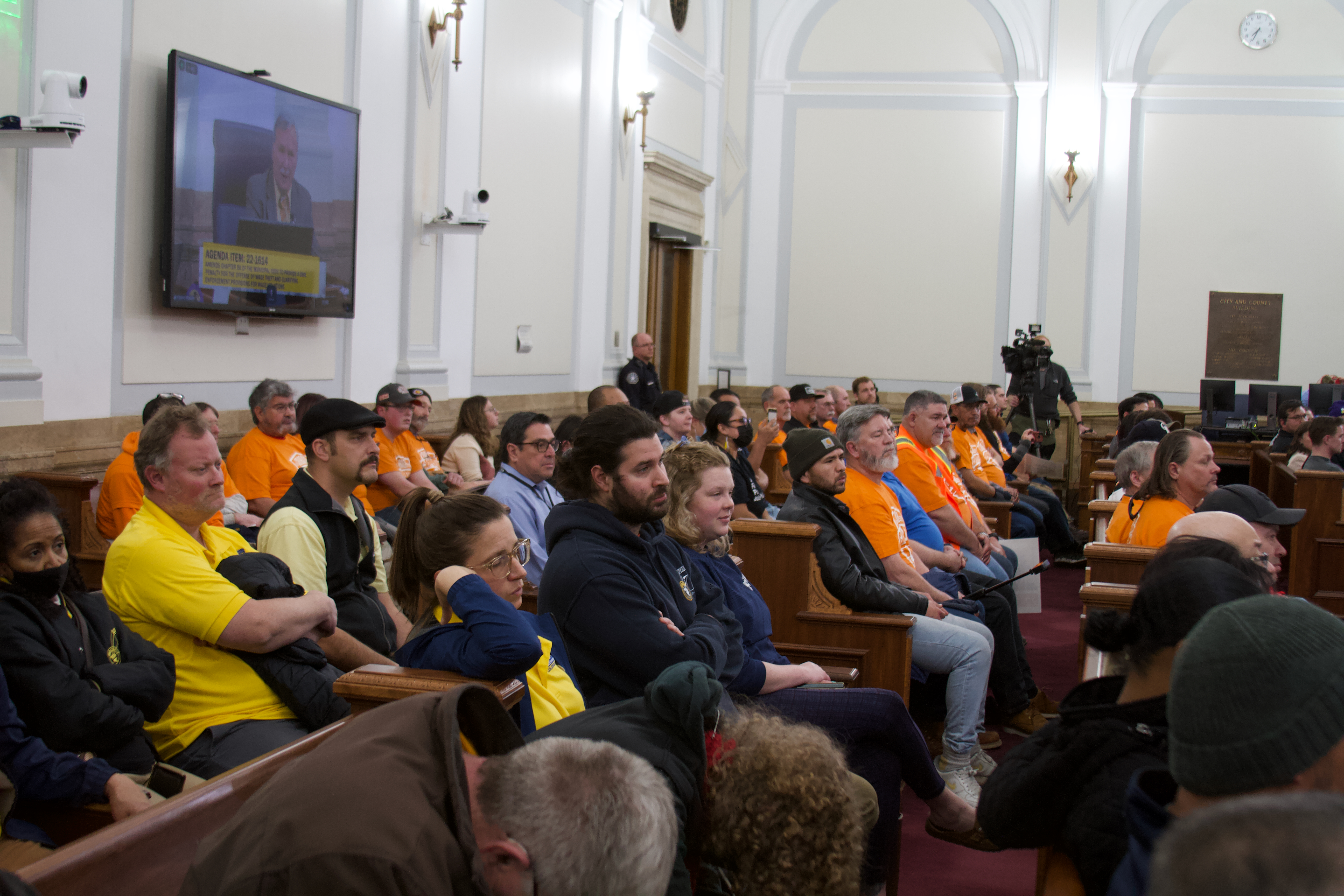 Members of the public sit in the city council chambers during a courtesy public hearing on wage theft. Council chambers filled with people, most clad in orange shirts of the Local 555 union, and some had to watch the meeting from the overflow room. (Alex Edwards/The Denver Gazette) (ALEX EDWARDS/THE DENVER GAZETTE)