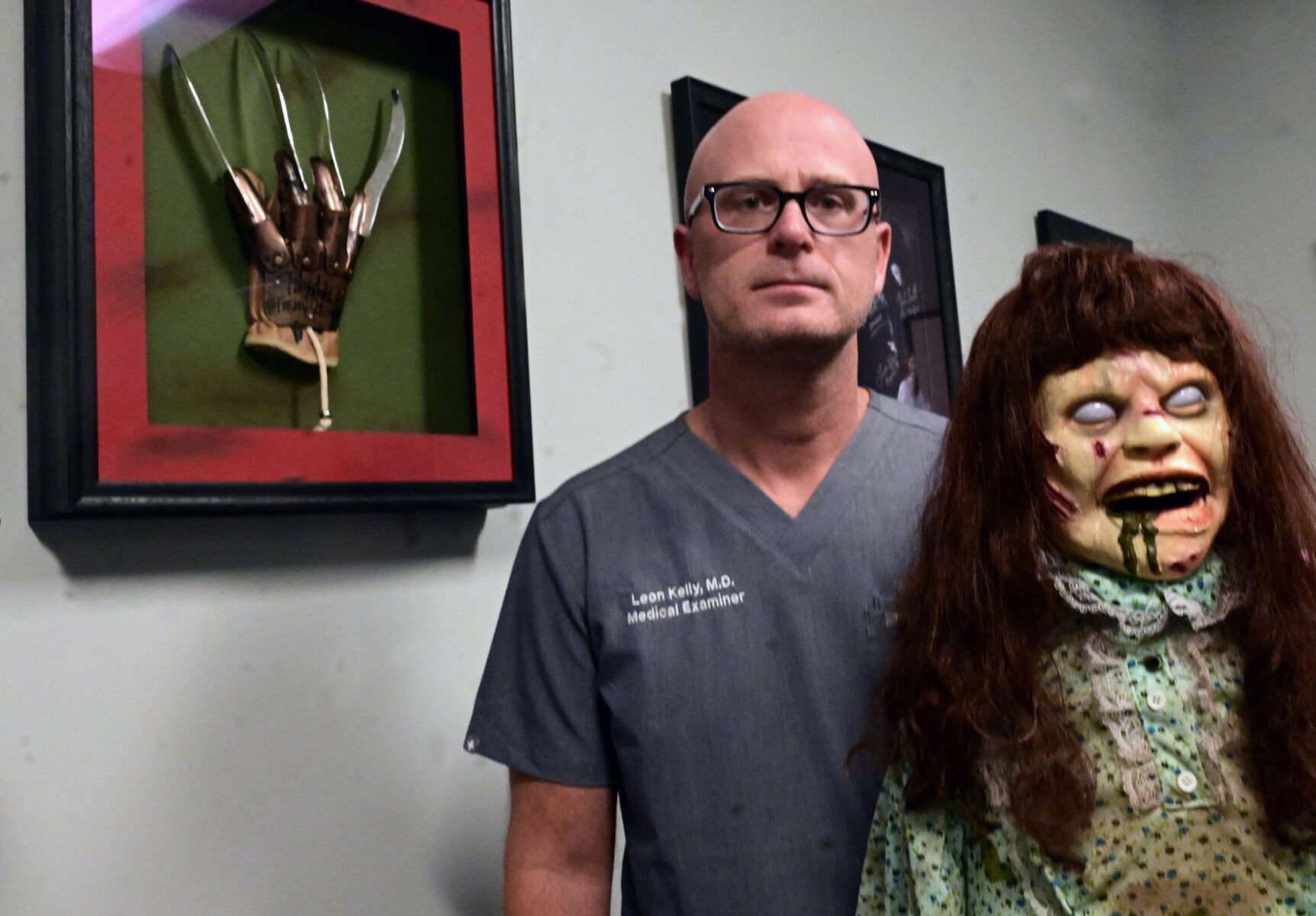 El Paso County Coroner Dr. Leon Kelly is a horror movie aficionado. “Linda,” a replica of Linda Blair in “The Exorcist,” and a Freddy Kreuger glove signed by actor Robert Englund are part of his office decor. Kelly co-founded and co-hosts the quarterly Six Feet Under Horror Film Festival at RoadHouse Cinemas. (Photos by Jerilee Bennett, The Gazette)