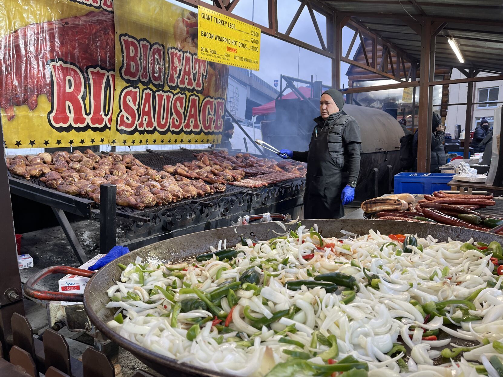 Armando Rivas keeps on eye on the meat as he grills sausage and chicken at a concession stand at the National Western Stock Show and Rodeo on Jan. 11, 2023. (NICOLE C. BRAMBILA/THE DENVER GAZETTE)