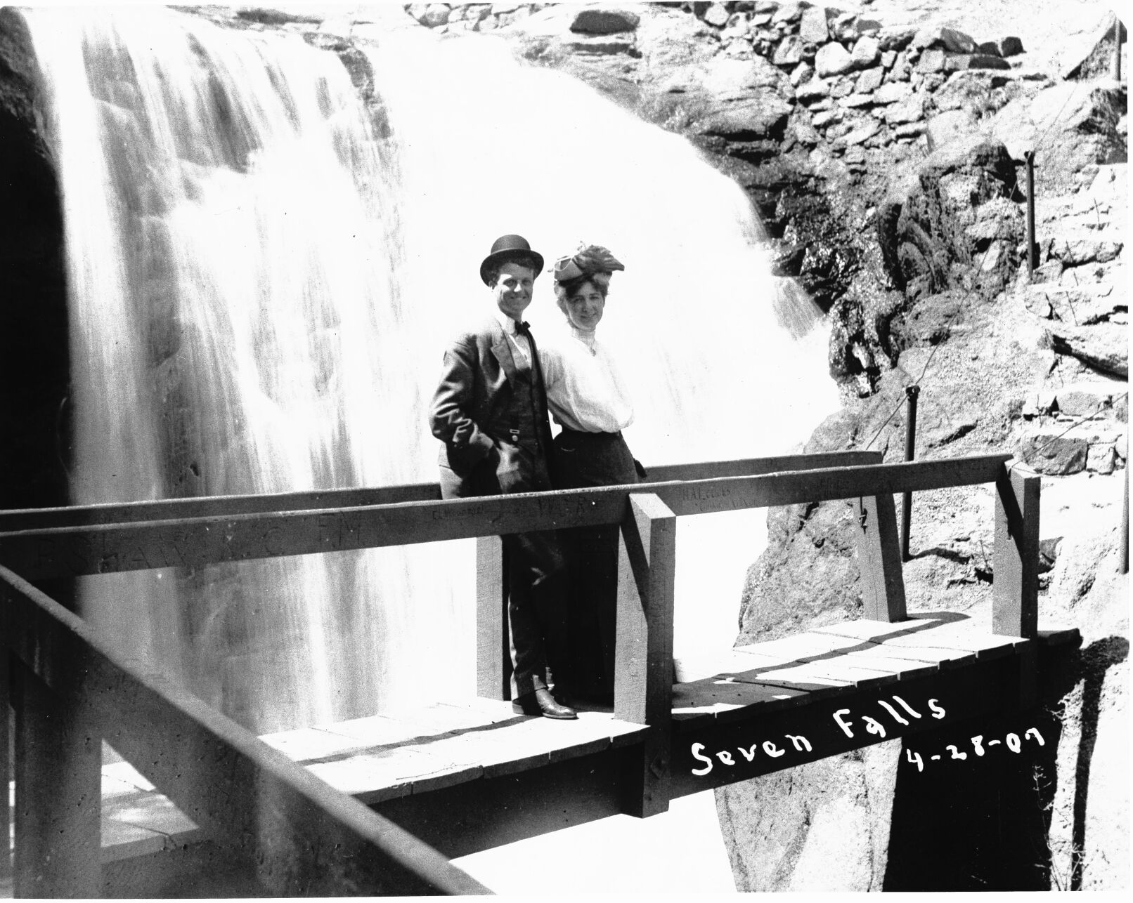 A man and woman stand on a wooden bridge with a waterfall in the background in this photo from 1907. Photo identified as “Seven Falls 4-28-07” on print. The couple is identified as Eddie and Pearl Dennis on the back of the photo. (Margaretta M. Boas Photograph Collection, courtesy of Pikes Peak Library District, 001-577)
