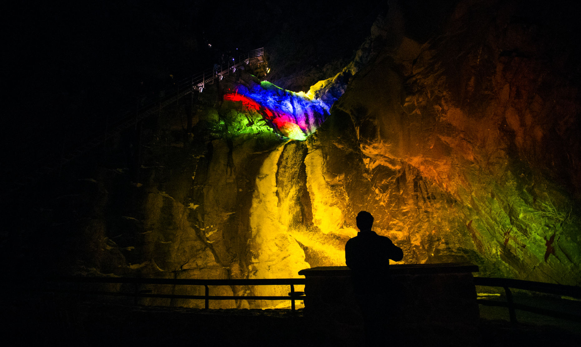 A spectator looks at the brightly colored falls Saturday, Nov. 19, 2016, during the Winter Lights celebration at The Broadmoor Seven Falls. (The Gazette, Christian Murdock) (CHRISTIAN MURDOCK, THE GAZETTE)